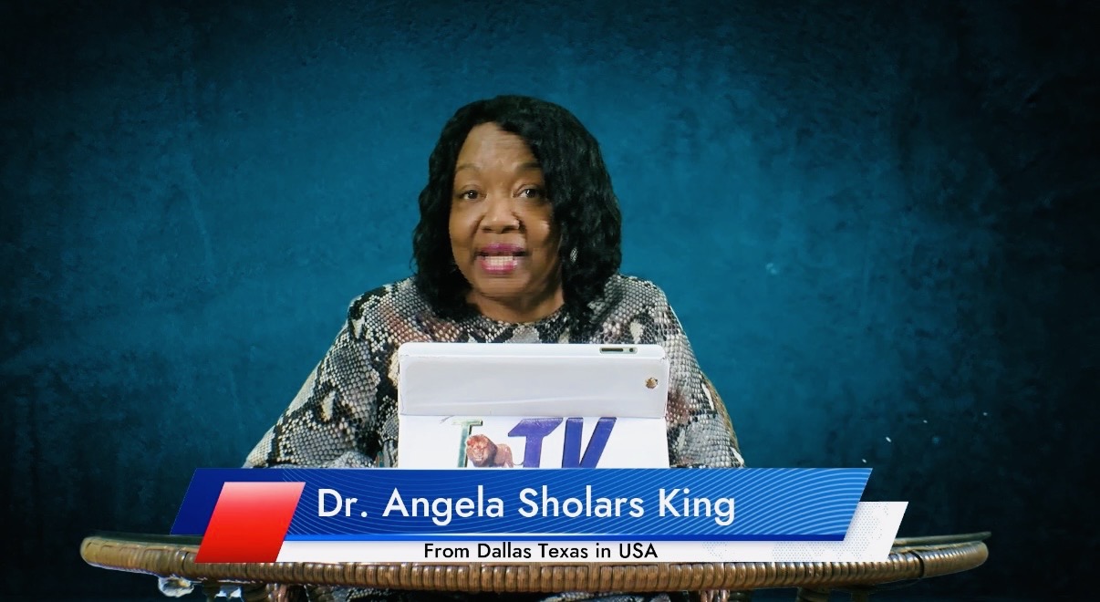 Woman with curly hair sitting at a table with a laptop, blue background, nameplate reads Dr. Angela Sholars King.