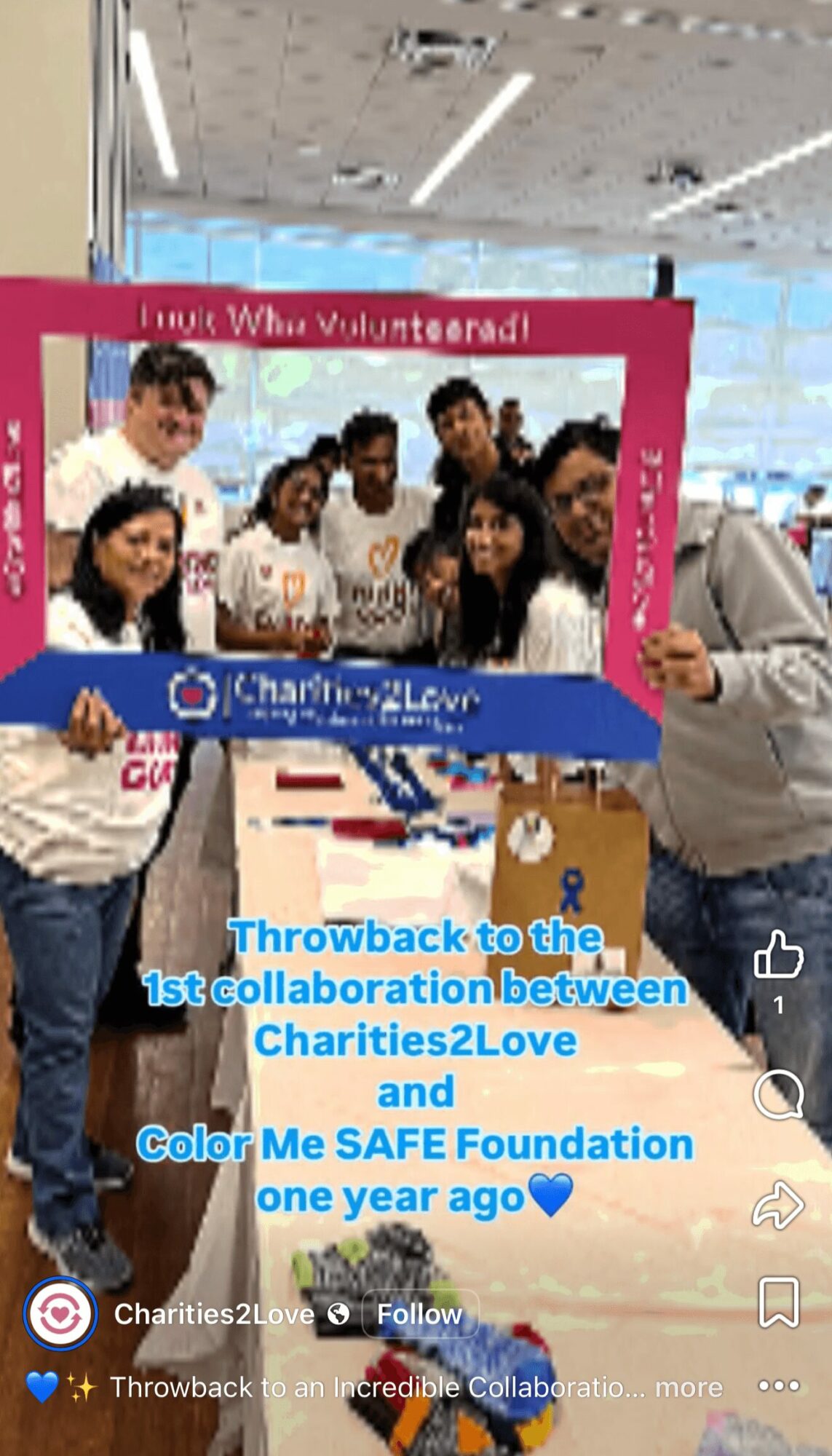 Group of people holding a pink and blue frame at an indoor event, smiling and posing for the photo.