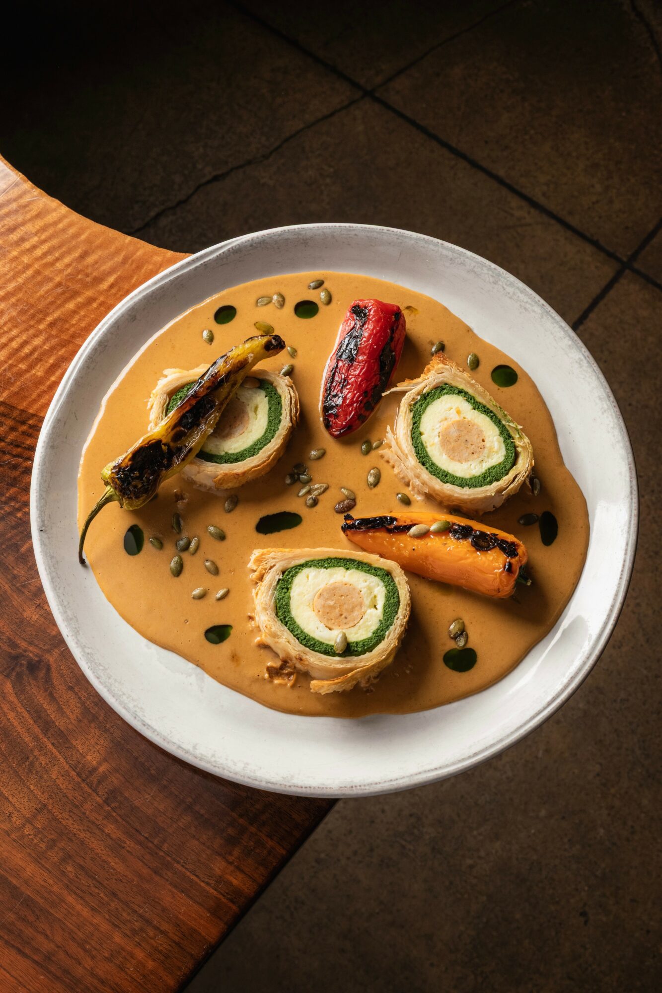 Bowl of curry with sliced vegetables and black seeds on top, served on a white plate.