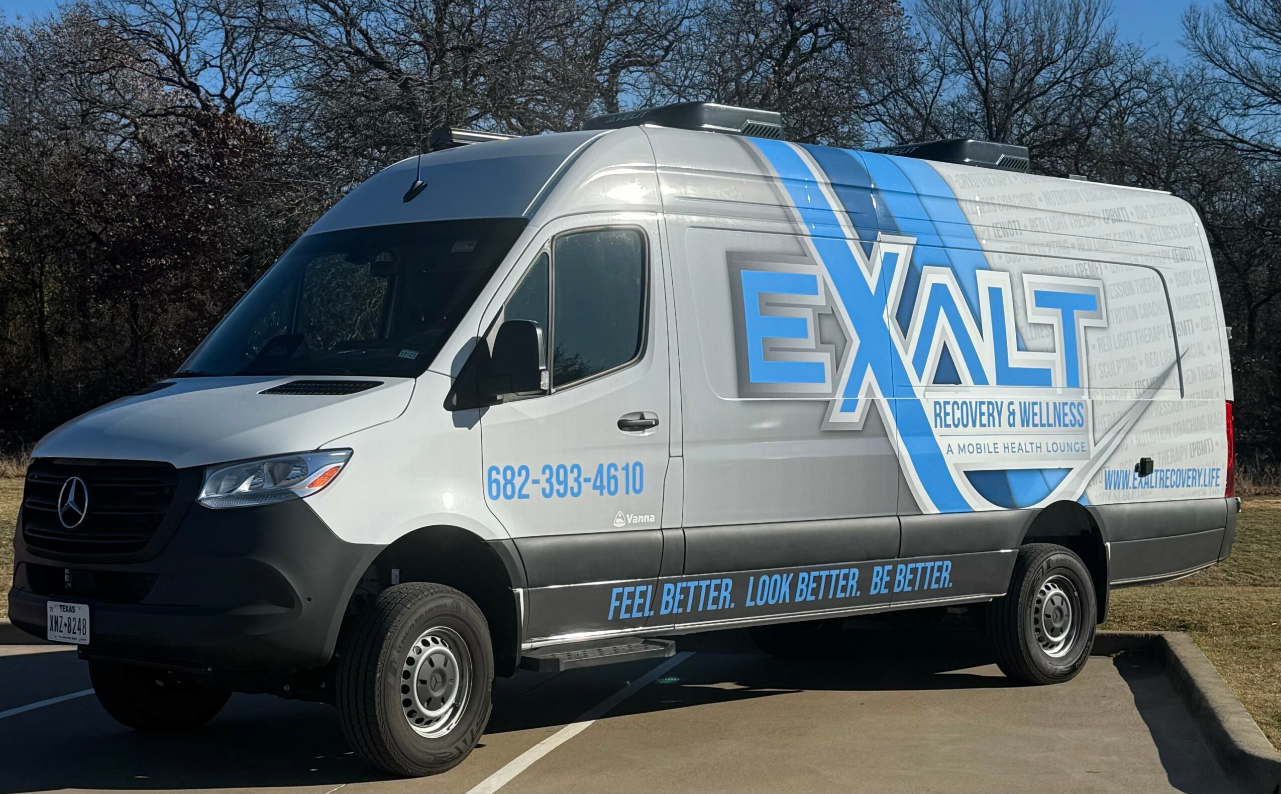 White van with blue and gray logo and text parked outdoors, trees in background.
