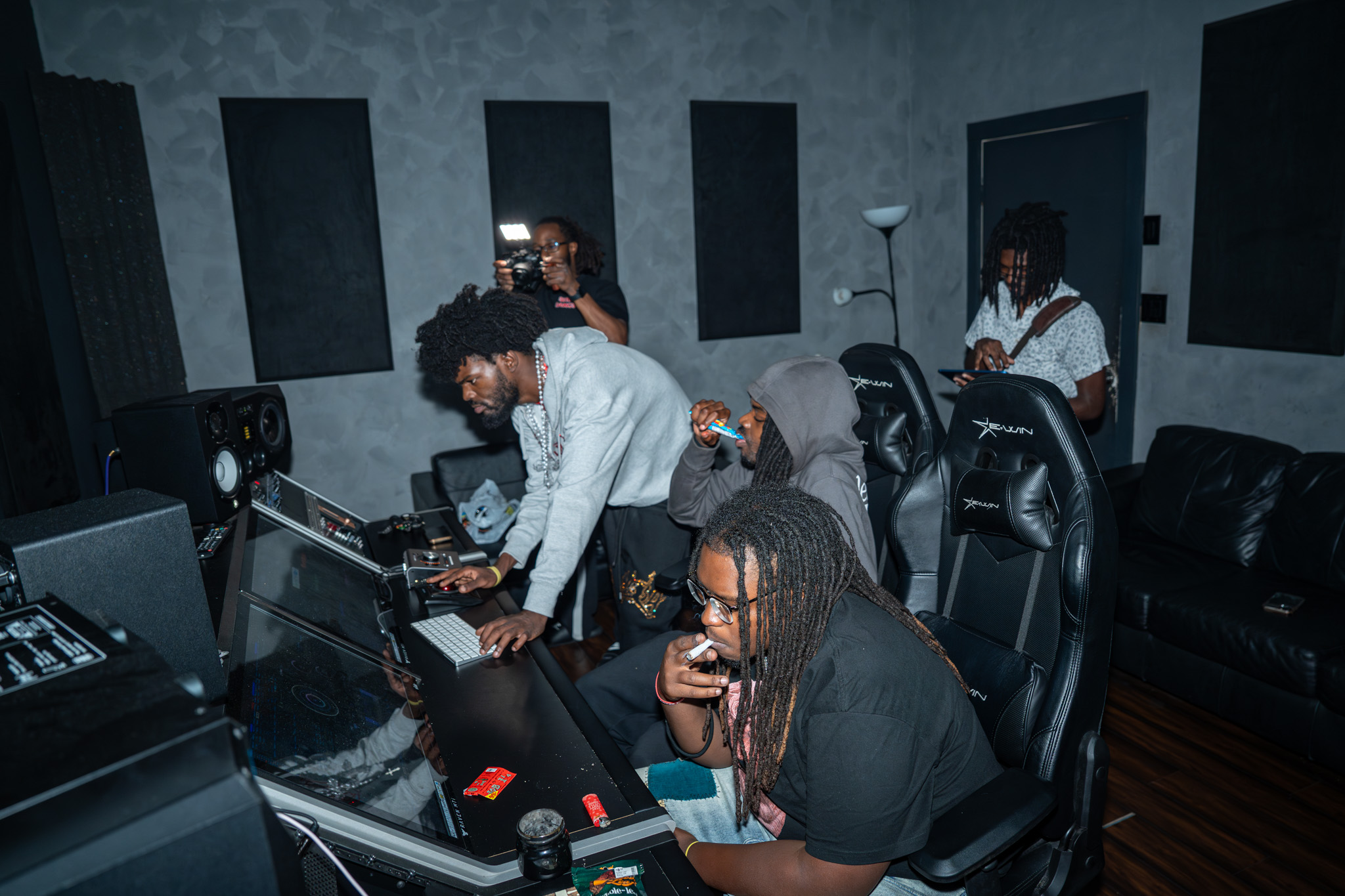 Group of people in a music studio working with audio equipment and computers, some wearing headphones.