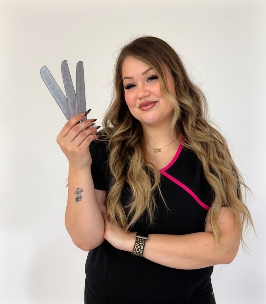 Young woman with long wavy hair holding a gray rabbit-shaped object, smiling, against a plain white background.