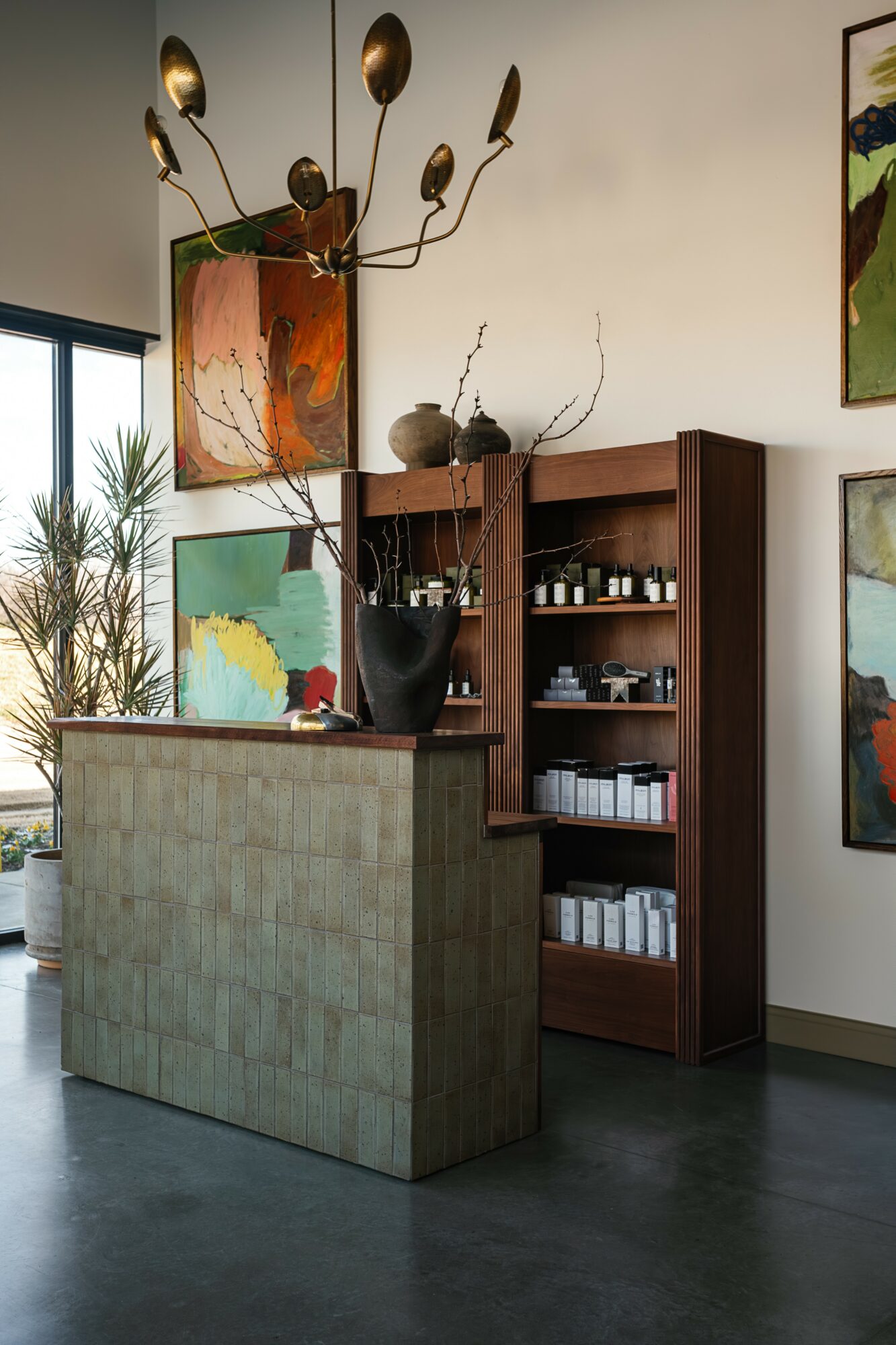 Interior space with a wooden bookshelf, a concrete counter, and decorative items including a large black vase and artwork.
