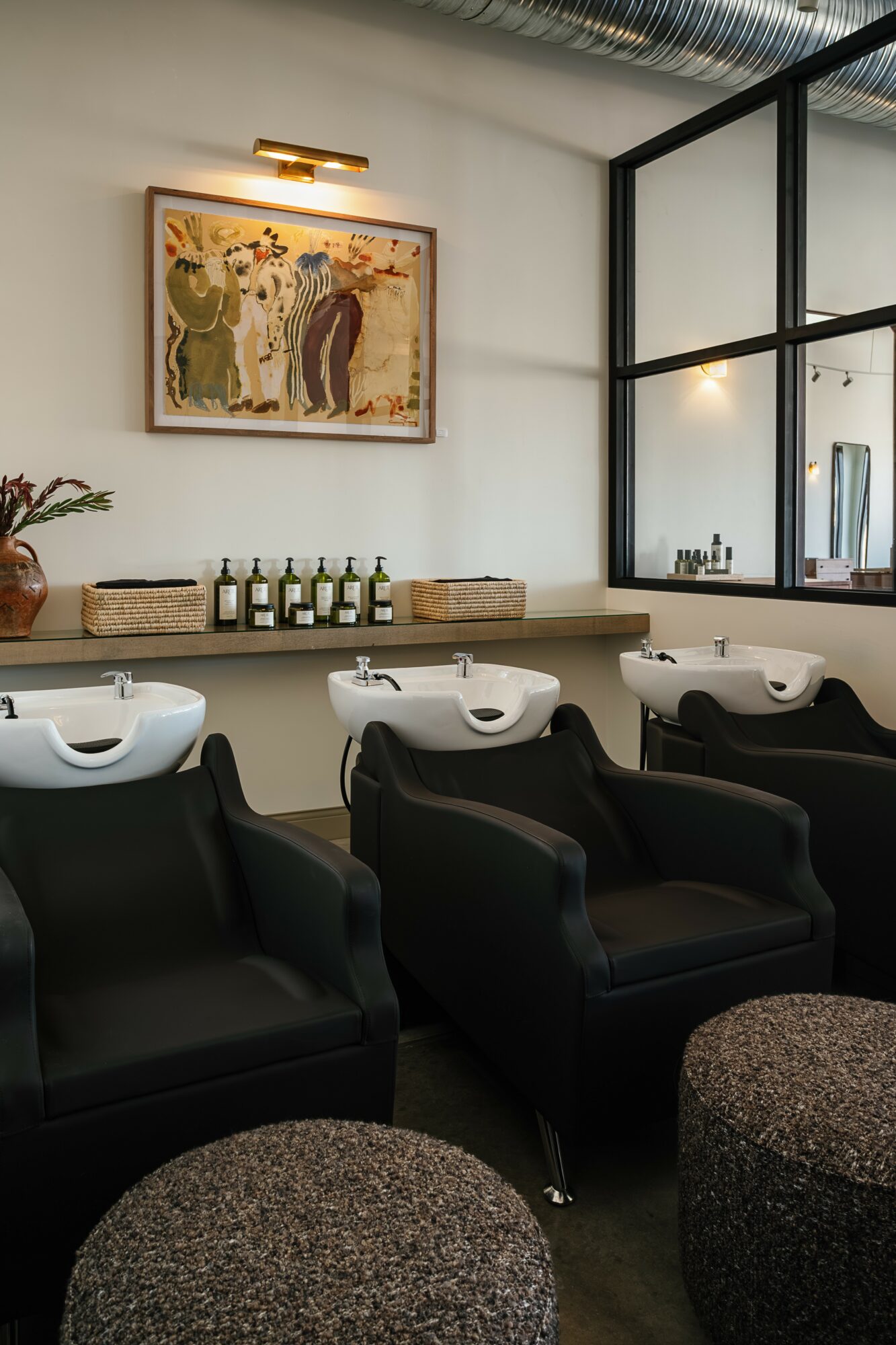 Salon with three black chairs, a window, and a painting on the wall.