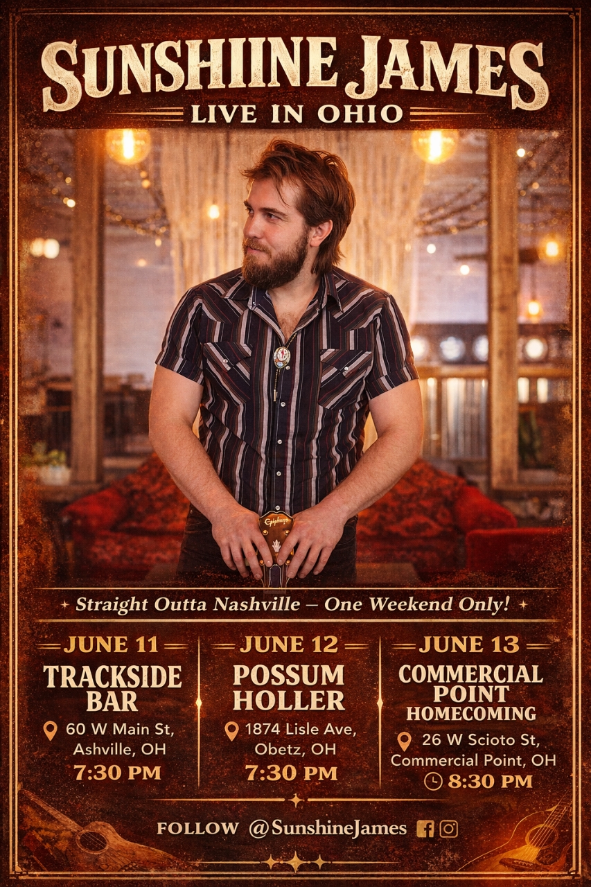 Man with beard and striped shirt standing indoors with warm lighting and curtains in background.