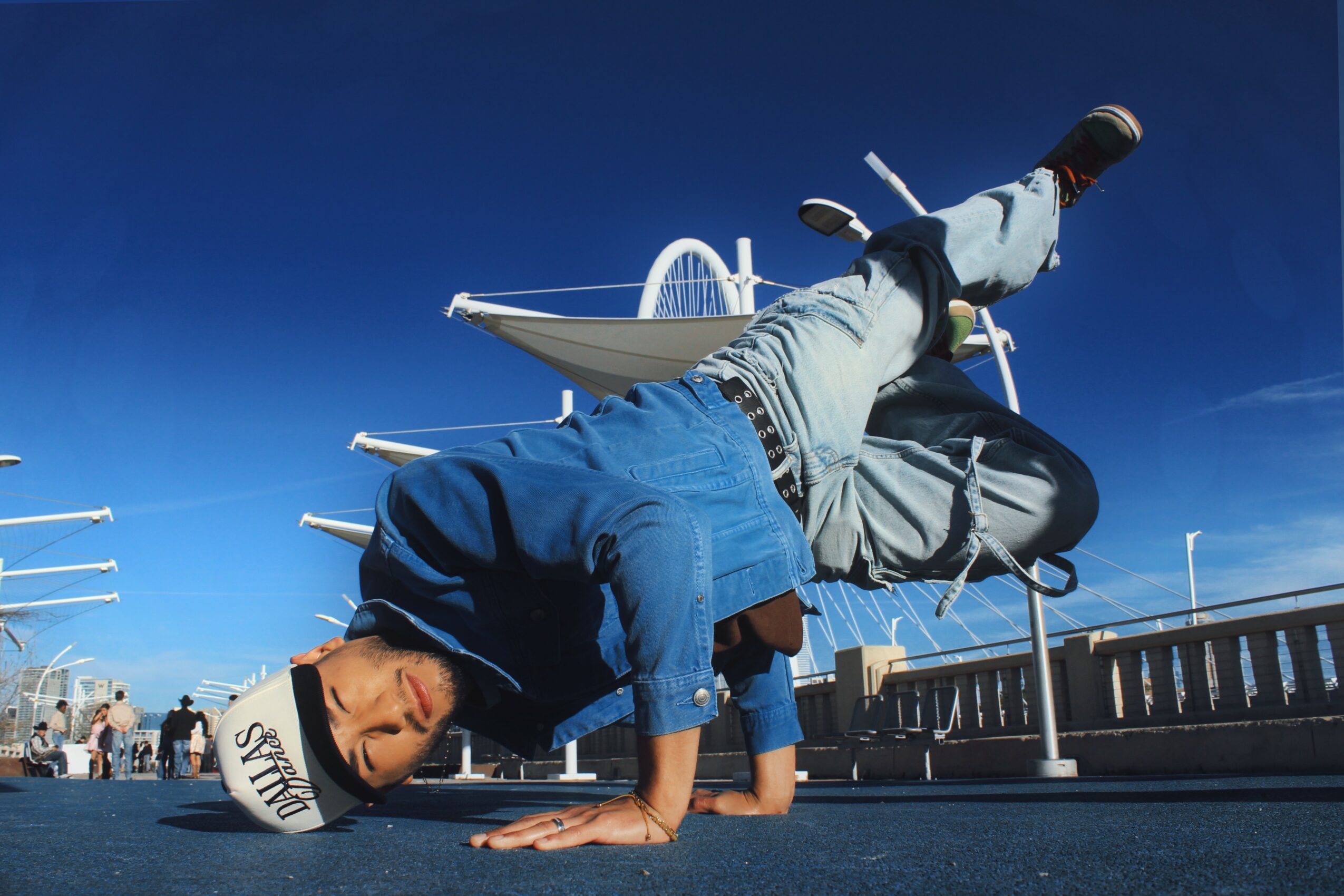 Person performing a handstand on a dock with boats in the background under a clear blue sky.