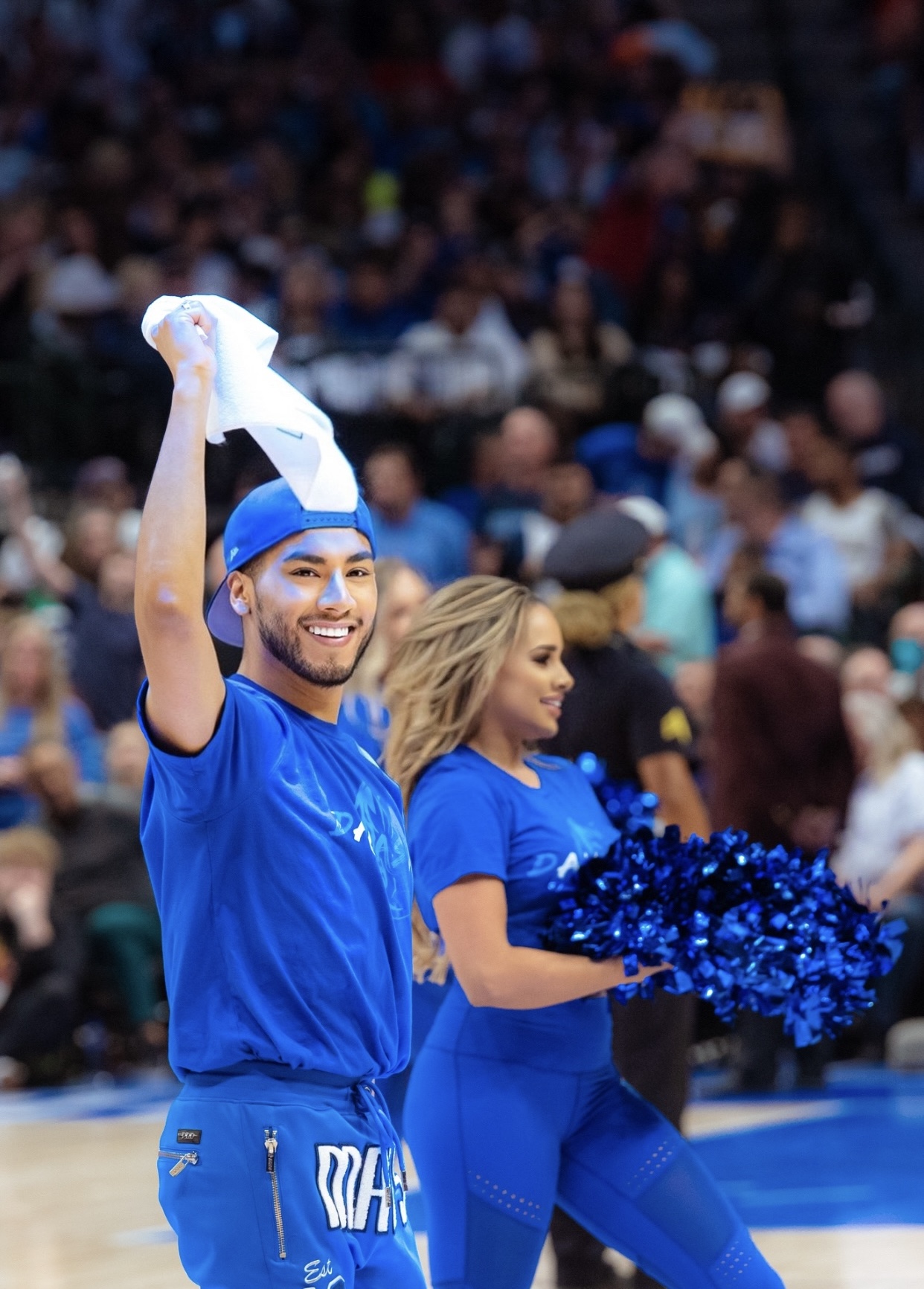 Person in blue sports attire holding a towel, smiling, with a crowd in the background.