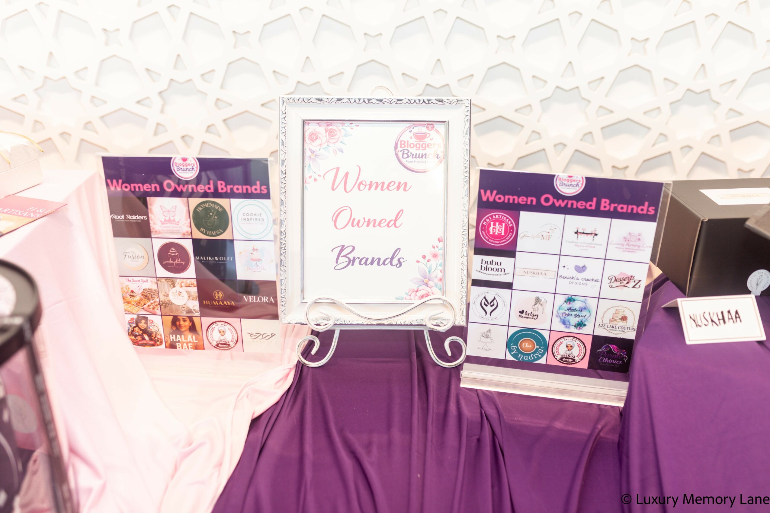 Display of women-owned brands with promotional materials and purple tablecloths.