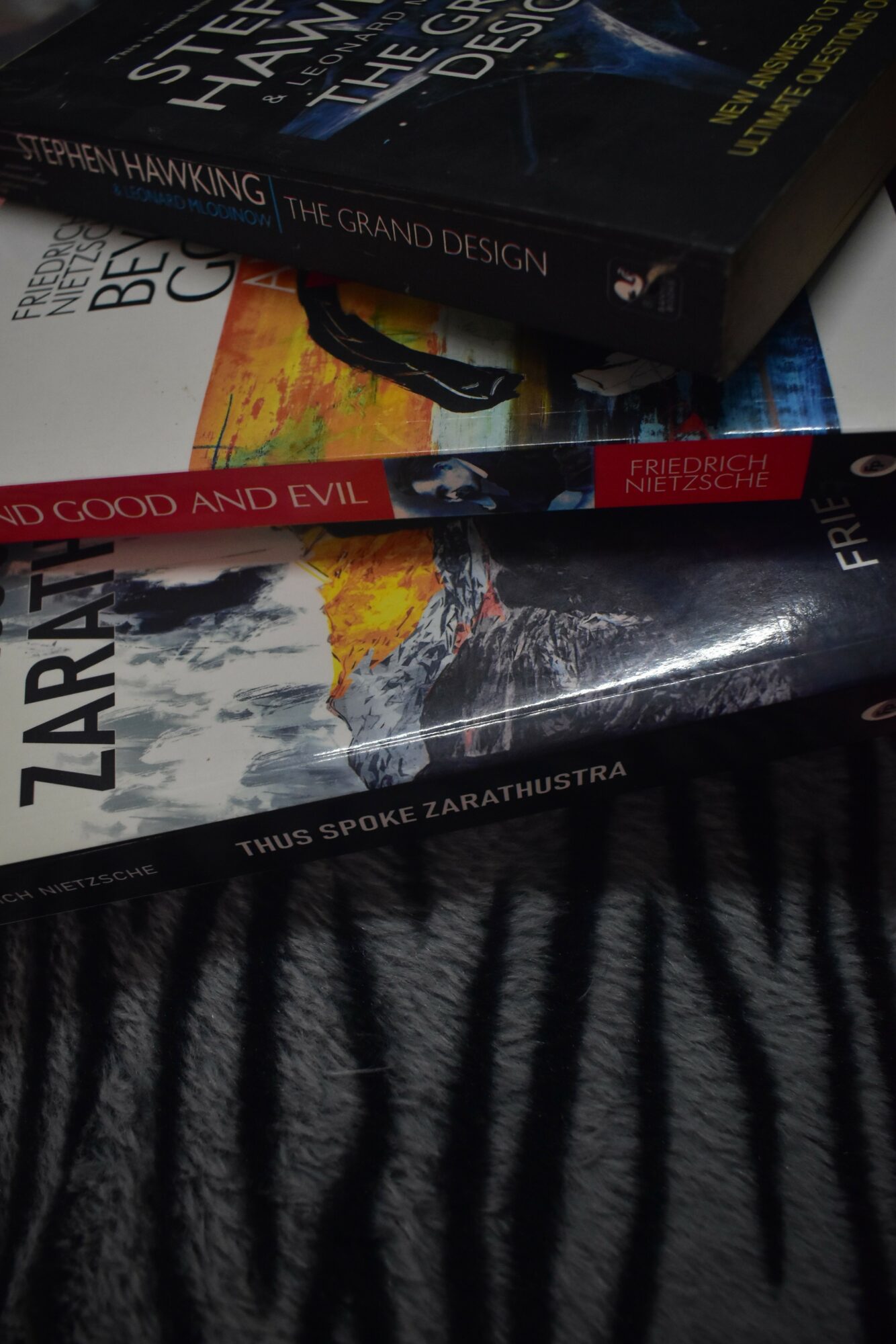 Stack of books on a black and white striped fabric surface, with titles visible on spines.