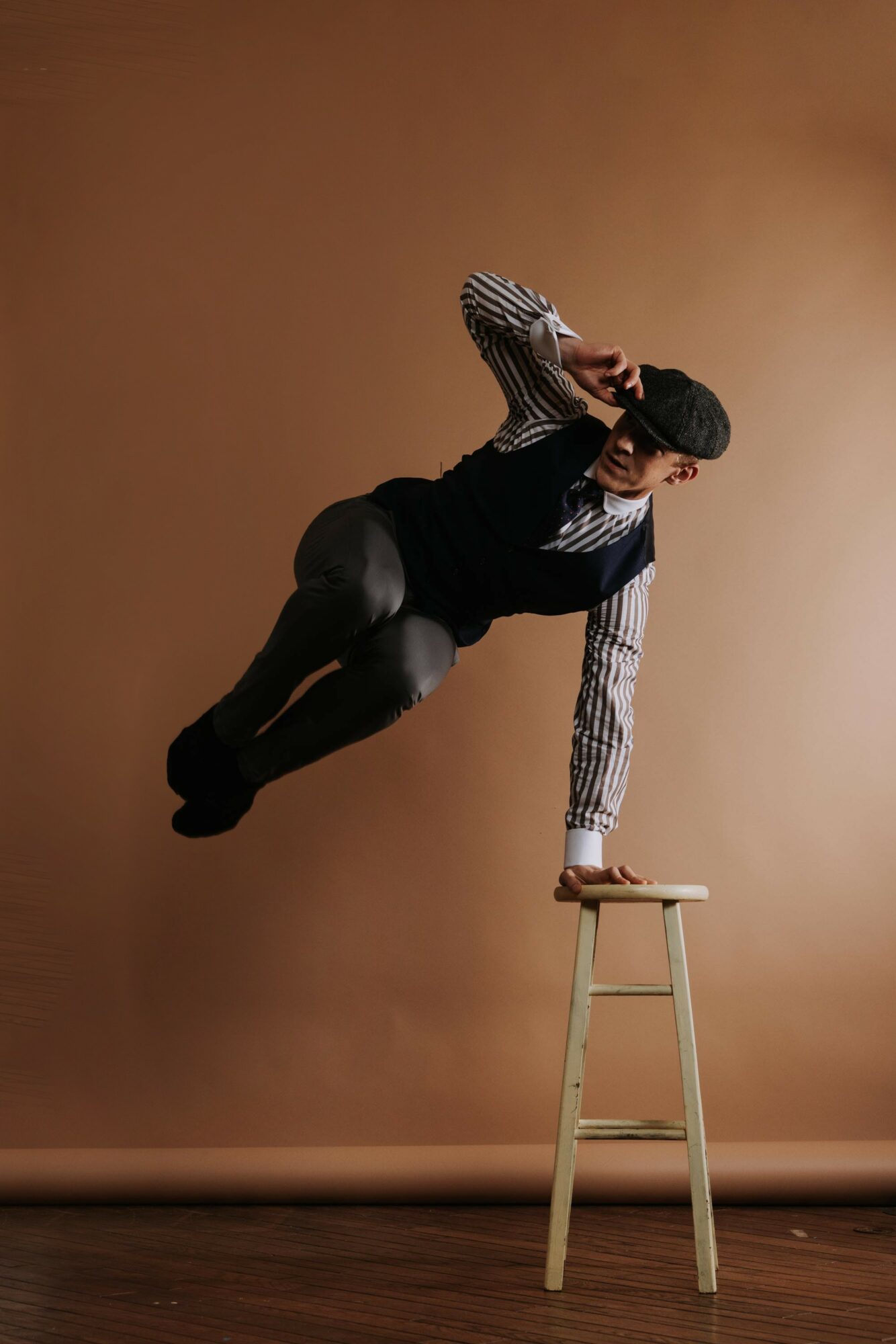 Person balancing on one hand on a stool, with legs extended and body parallel to the ground.