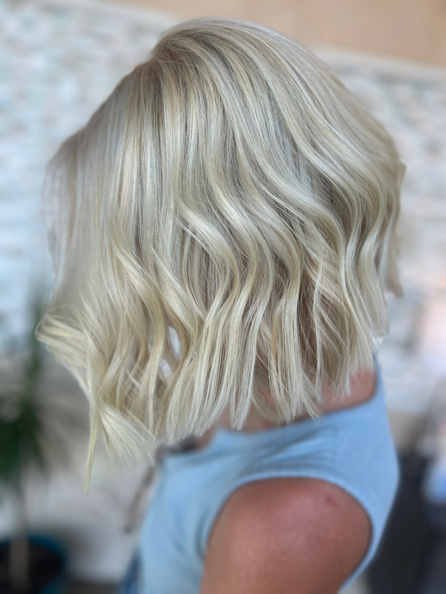 Blonde wavy bob hairstyle viewed from the back, with soft curls and layered cut.