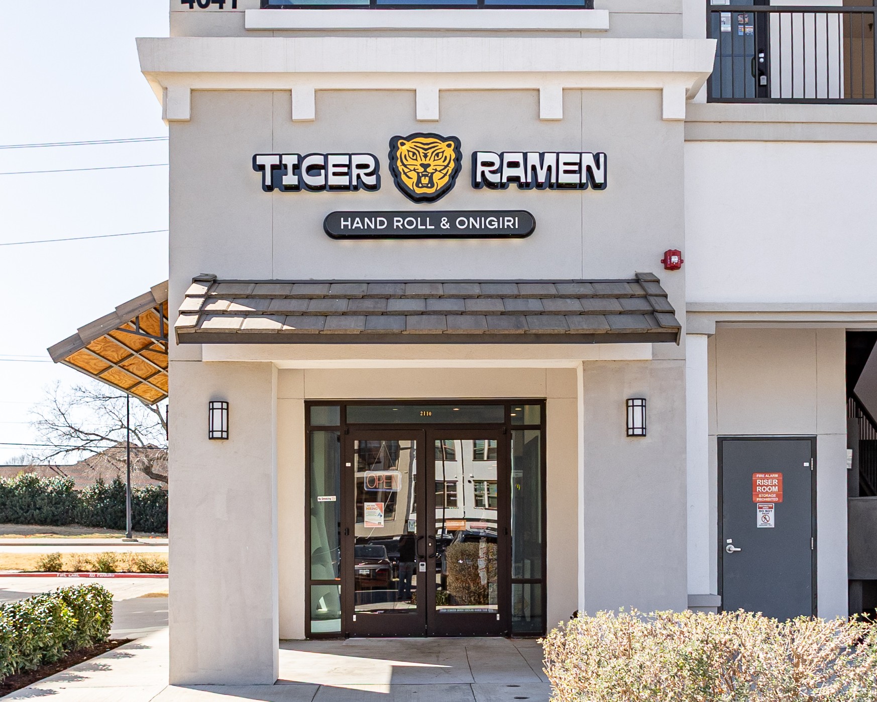 Storefront with sign reading 'TIGER RAMEN' and a tiger logo, entrance with glass doors, and a small awning.
