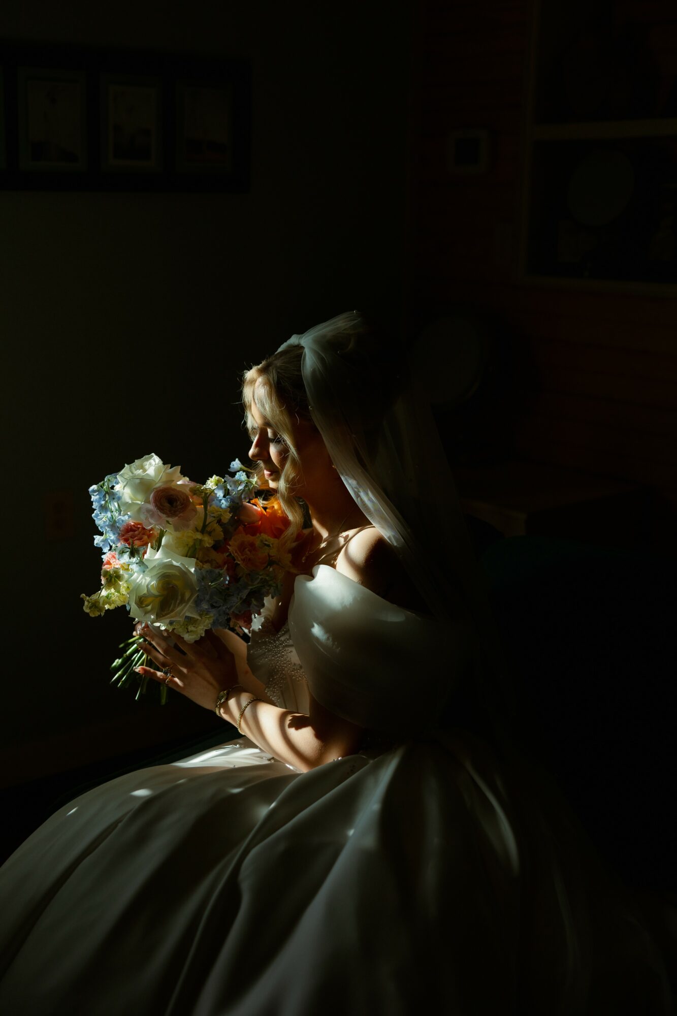 Person holding a bouquet of flowers, illuminated by light, with a dark background.