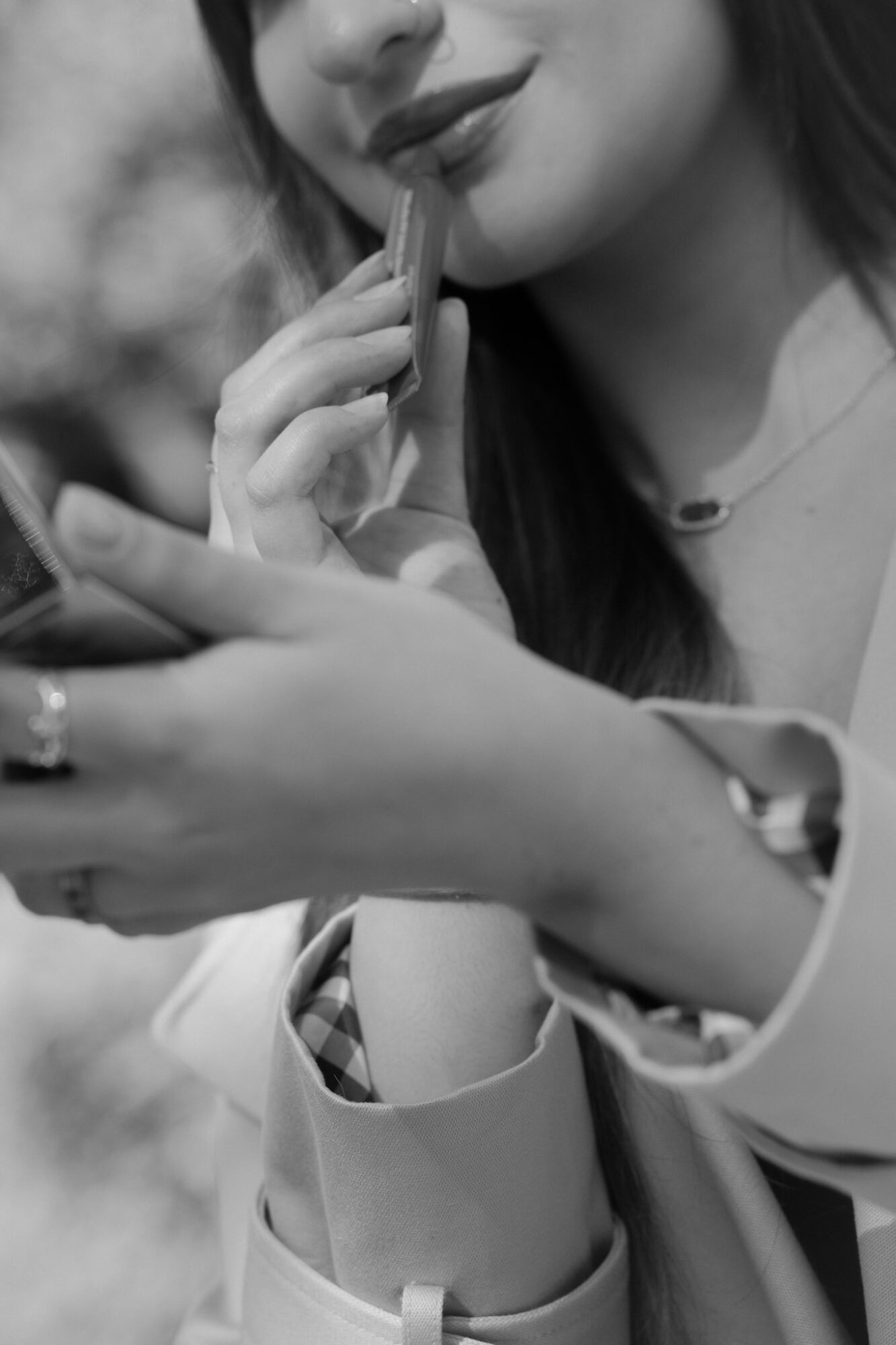 Close-up of a woman with lipstick, holding a phone and touching her lips with her finger.