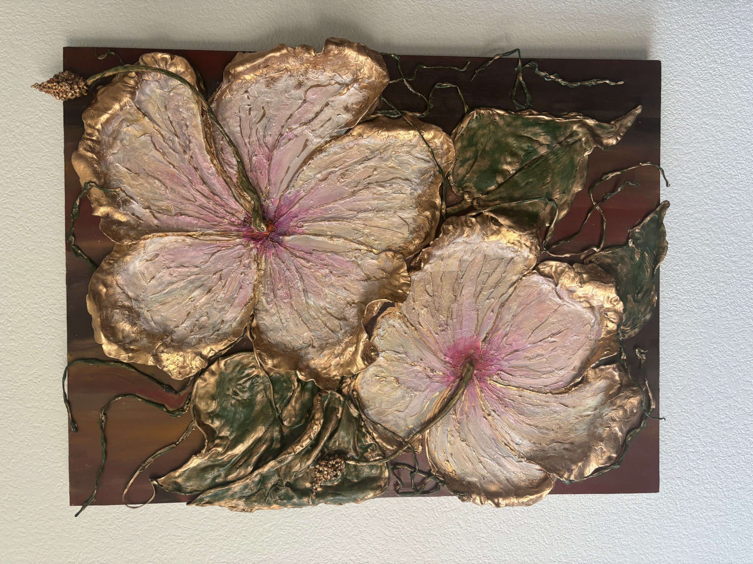Painting of two large flowers with pink and white petals, gold accents, and green leaves on a dark background.