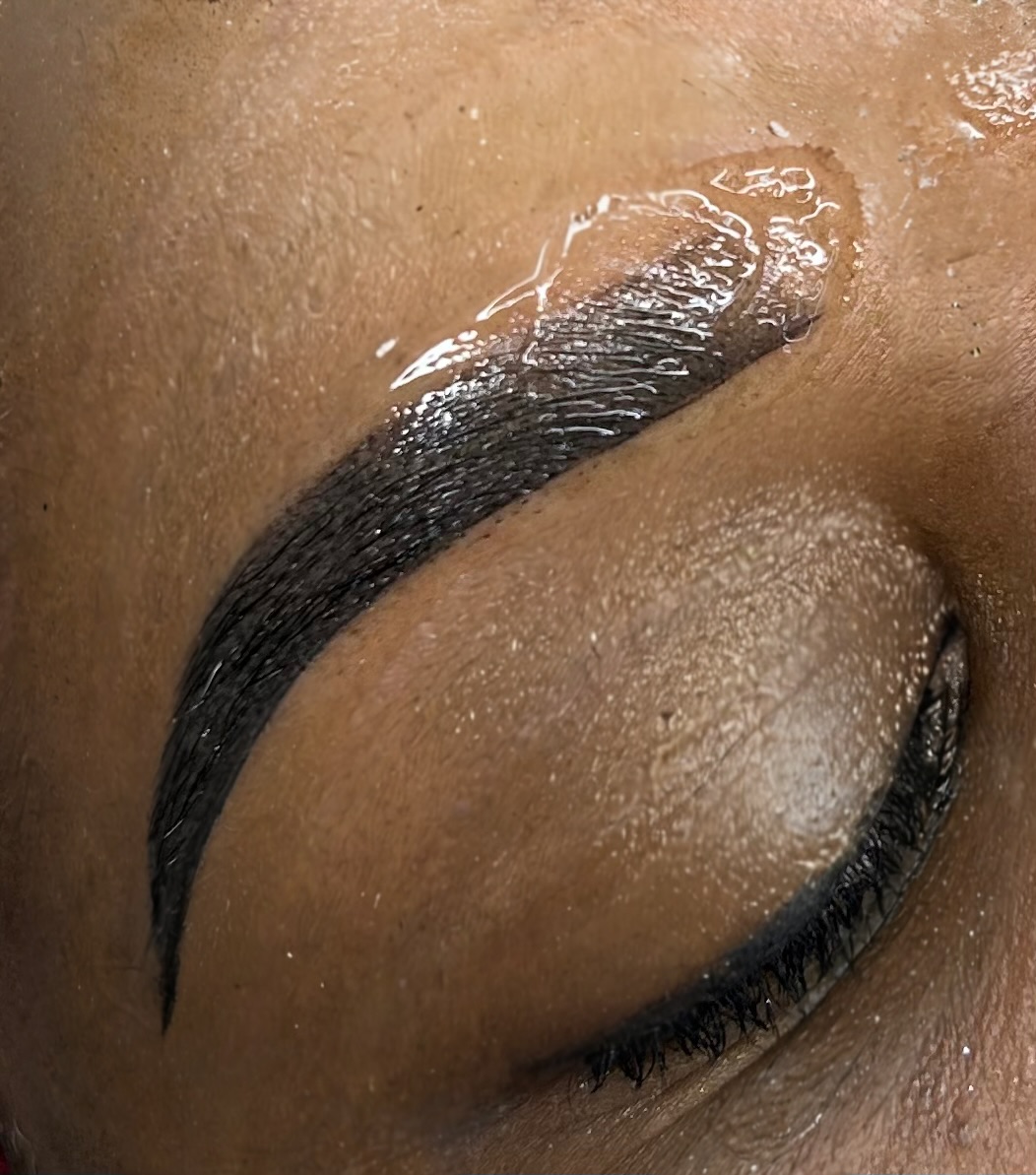 Close-up of a person's eye with well-defined eyebrow and closed eyelid, skin appears smooth and moisturized.