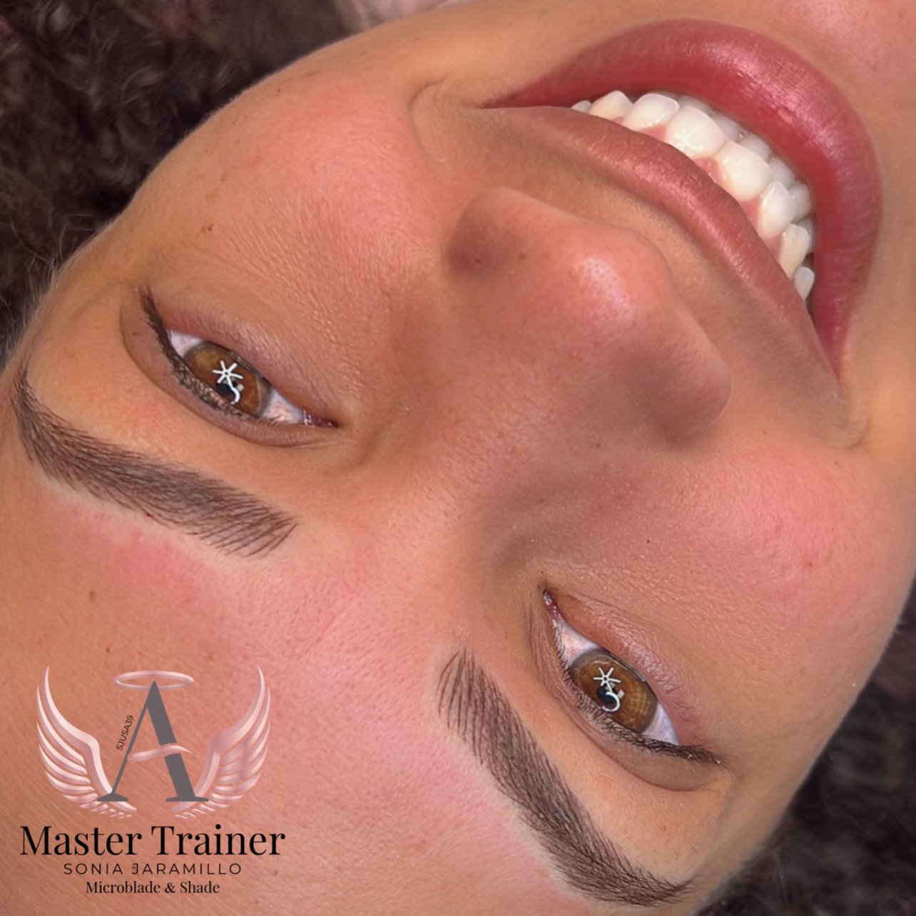 Close-up of a smiling person's face with visible eyebrows and eyes, upside down in the image.