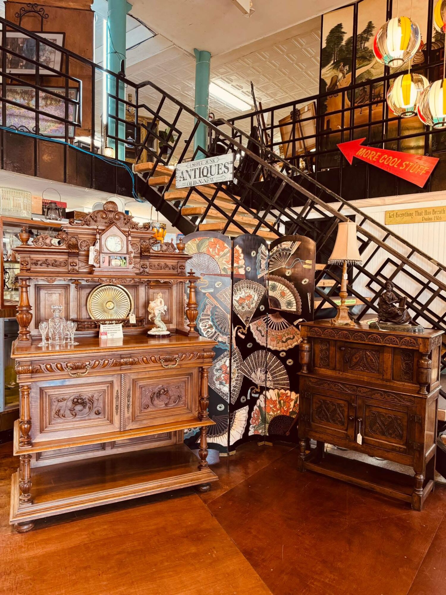 Antique wooden cabinet with ornate carvings and a glass display, next to a wooden chest of drawers, in an indoor setting.