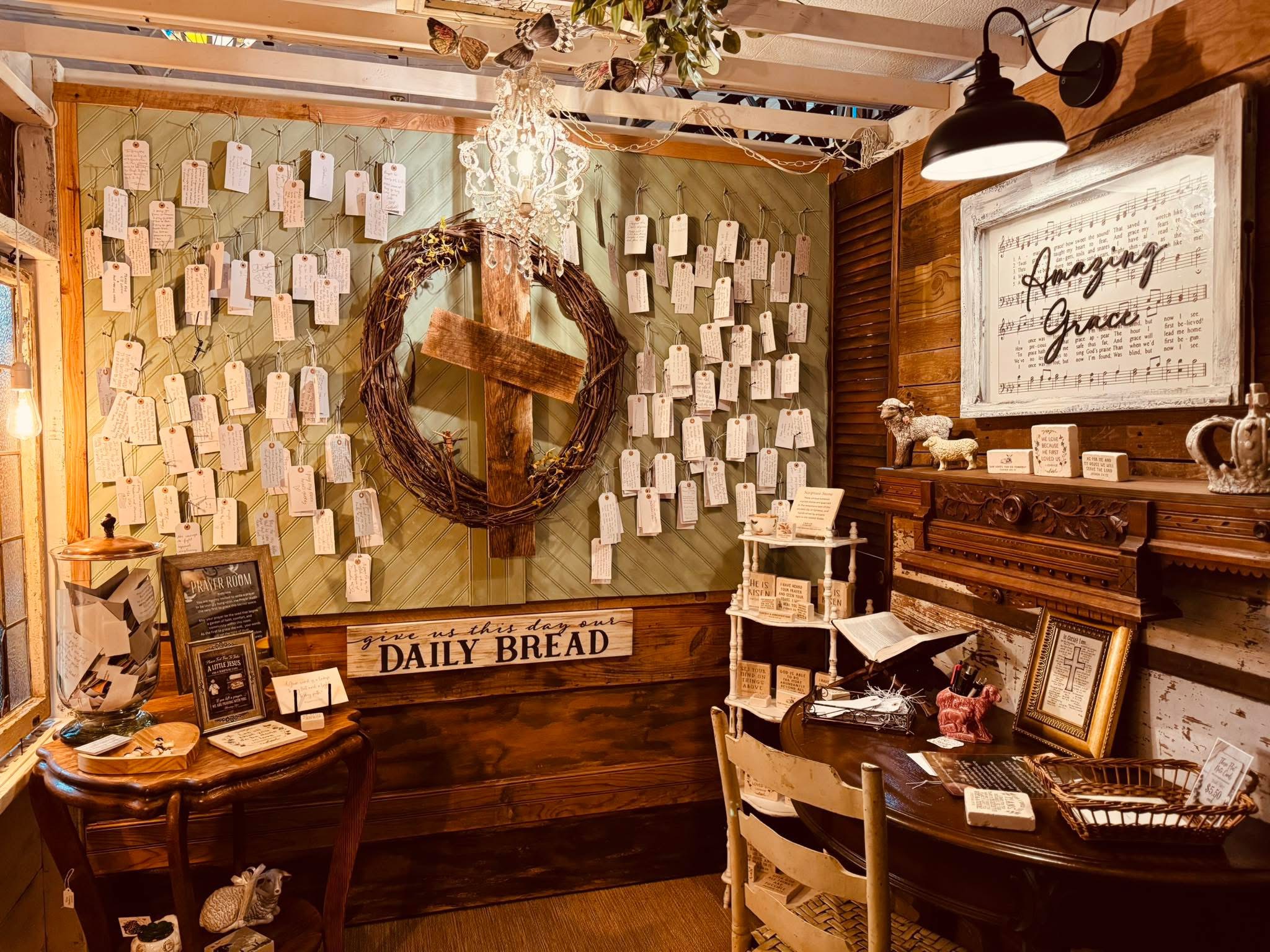 Decorative wall with a wreath, paper notes, and framed signs in a cozy room with wooden furniture.