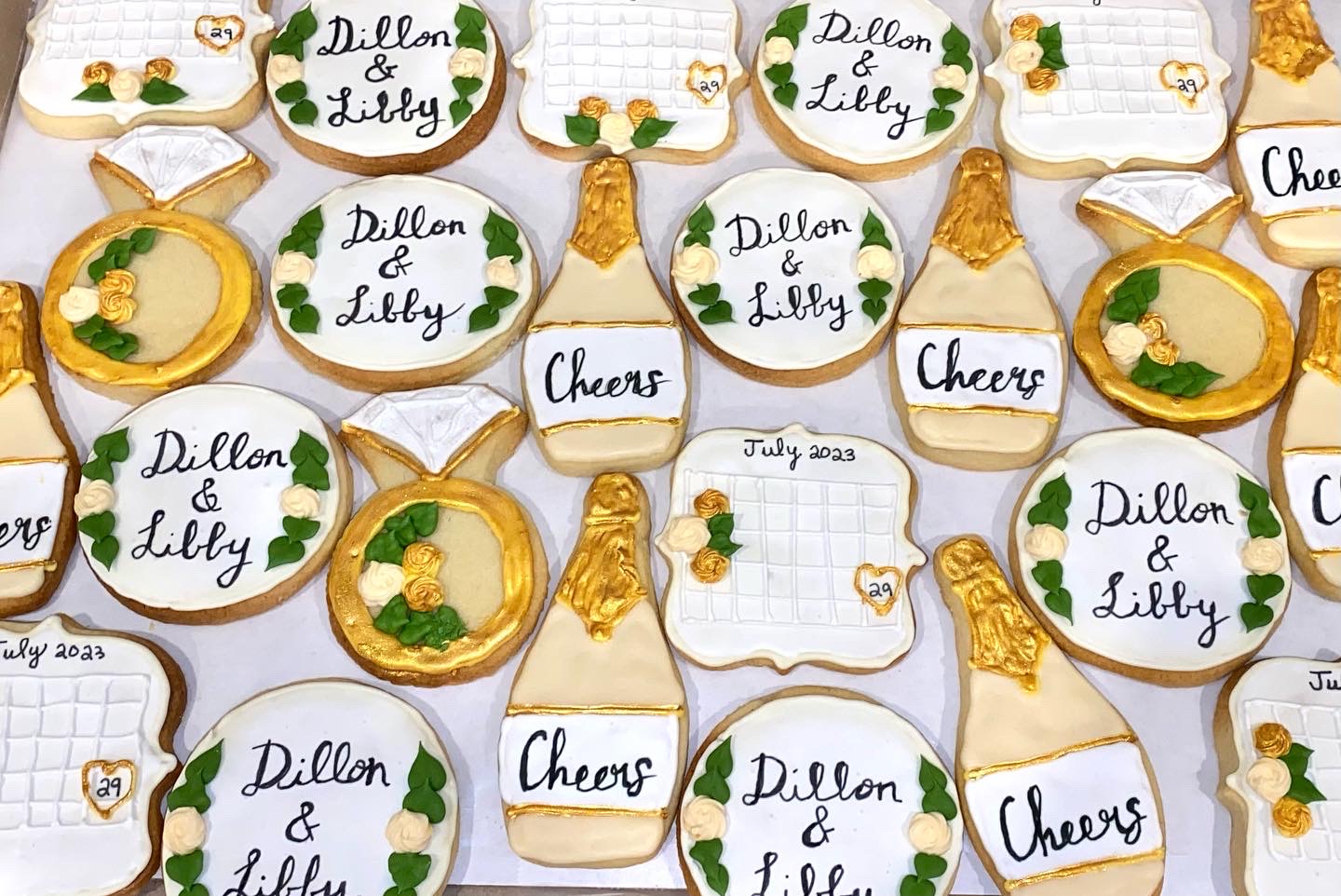 Collection of decorated cookies with personalized names, cheers, and yellow-green floral designs, arranged on a surface.