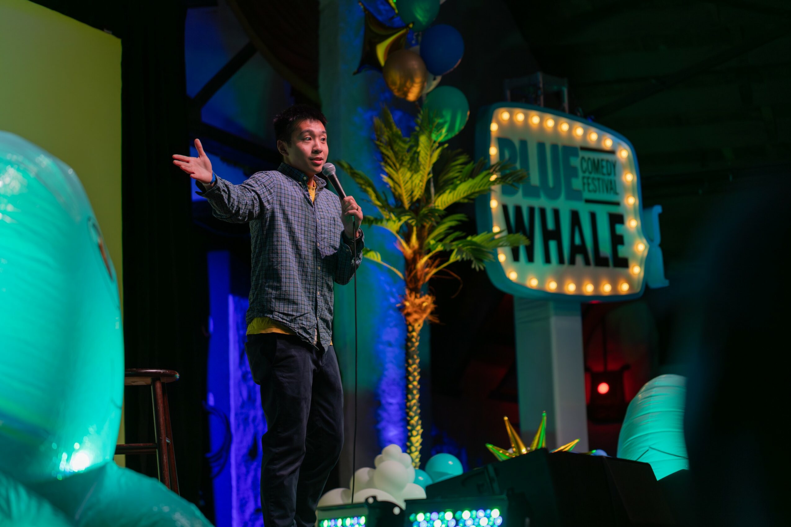Person performing on stage with colorful decorations and a sign that says 'Blue Whale'.