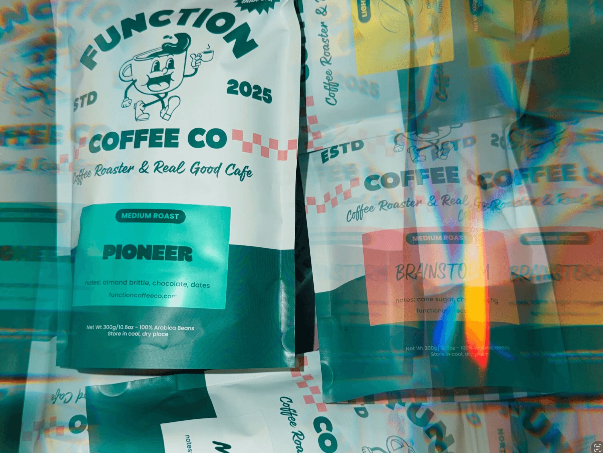 Coffee bag with text and logo, colorful reflections, and multiple similar bags in background.
