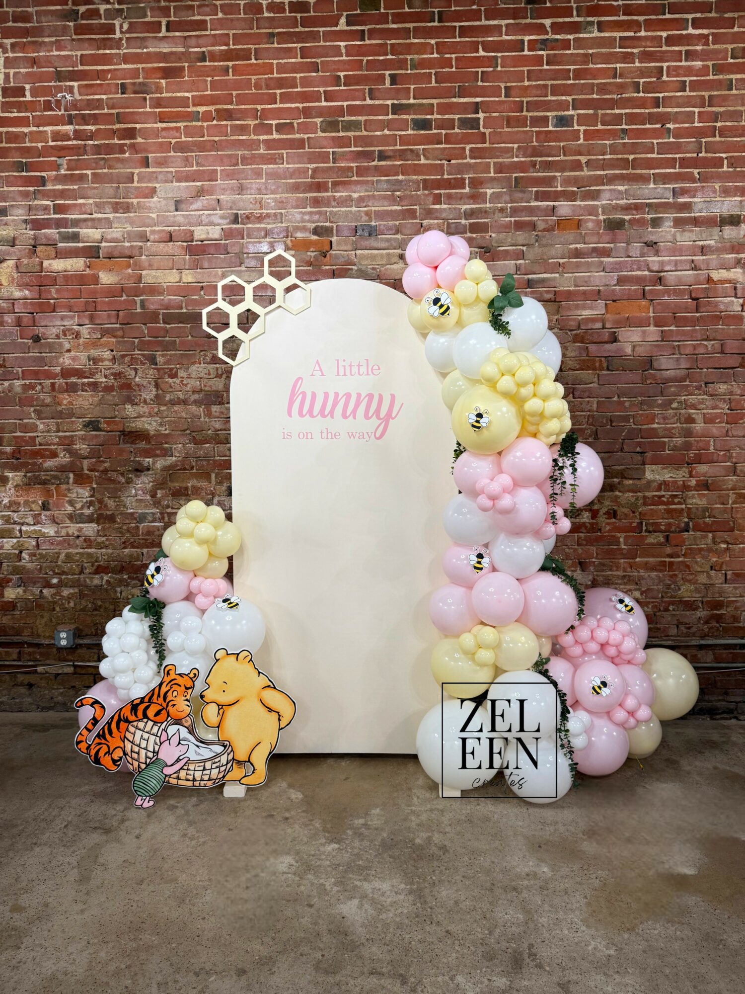 Decorative display with balloons, a white board, and cartoon character cutouts against a brick wall.