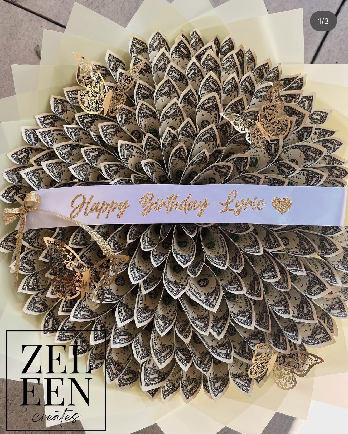 Decorative flower-shaped arrangement of coffee beans with a birthday message ribbon, on a light background.