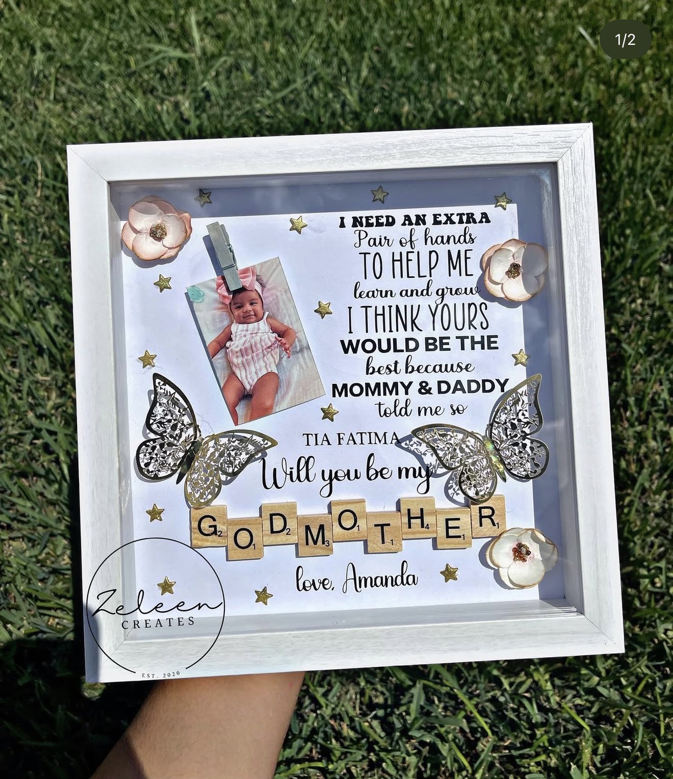 Decorative framed collage with a photo, text, butterflies, and gold letter tiles on grass.