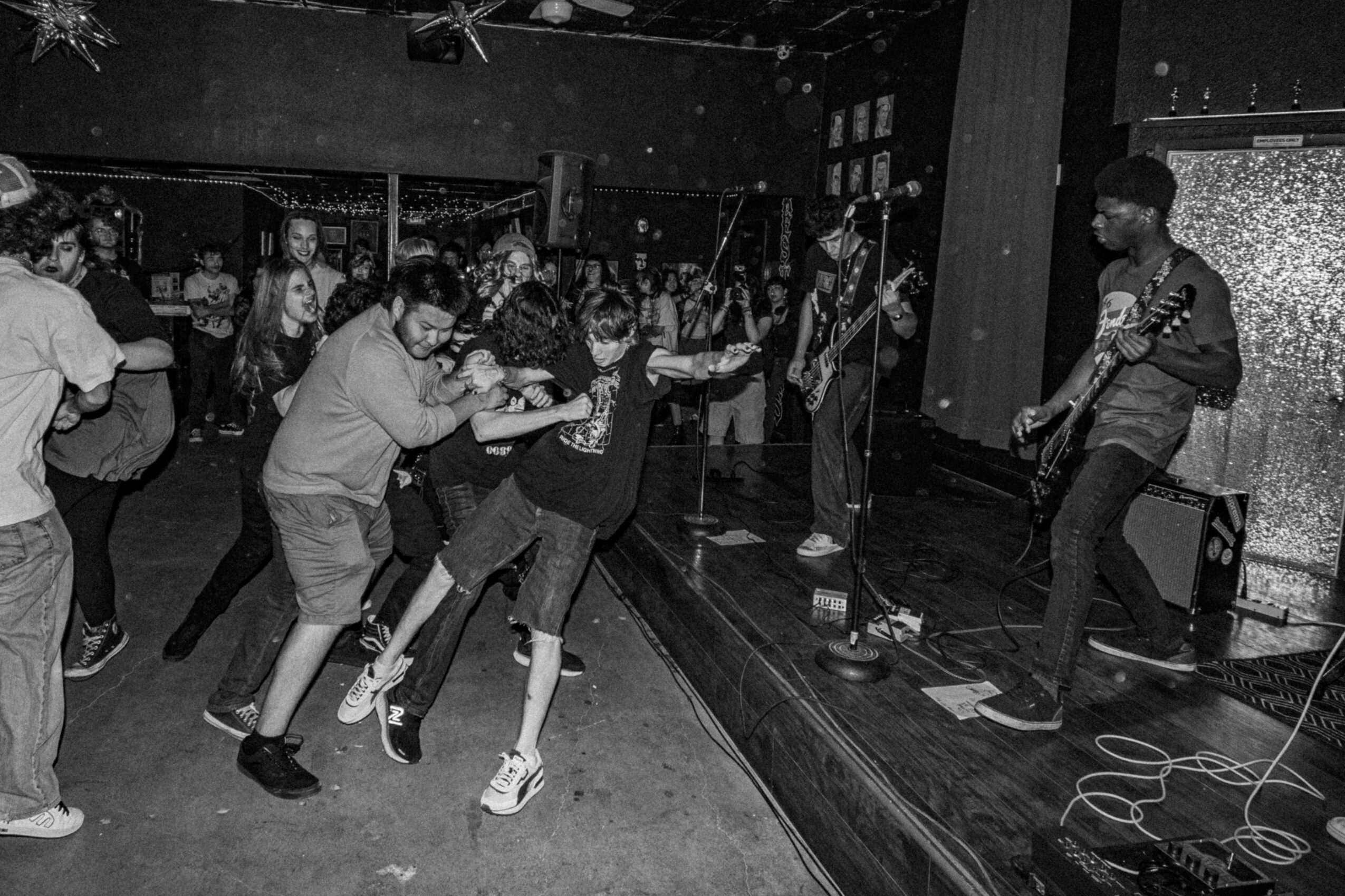 People dancing and a musician playing guitar on stage in a lively indoor setting.