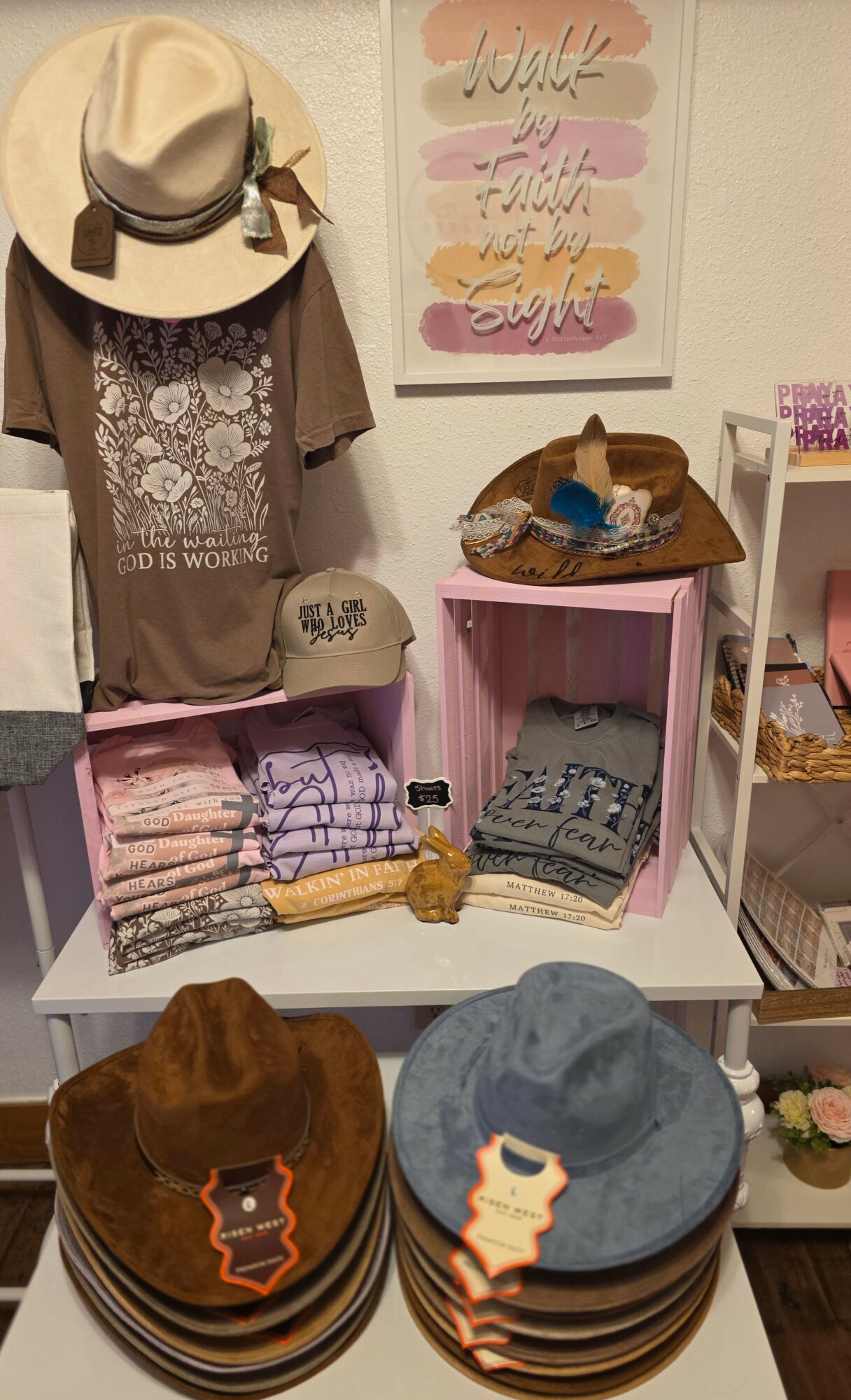 Display of hats, folded clothes, and accessories on shelves and tables in a boutique store.