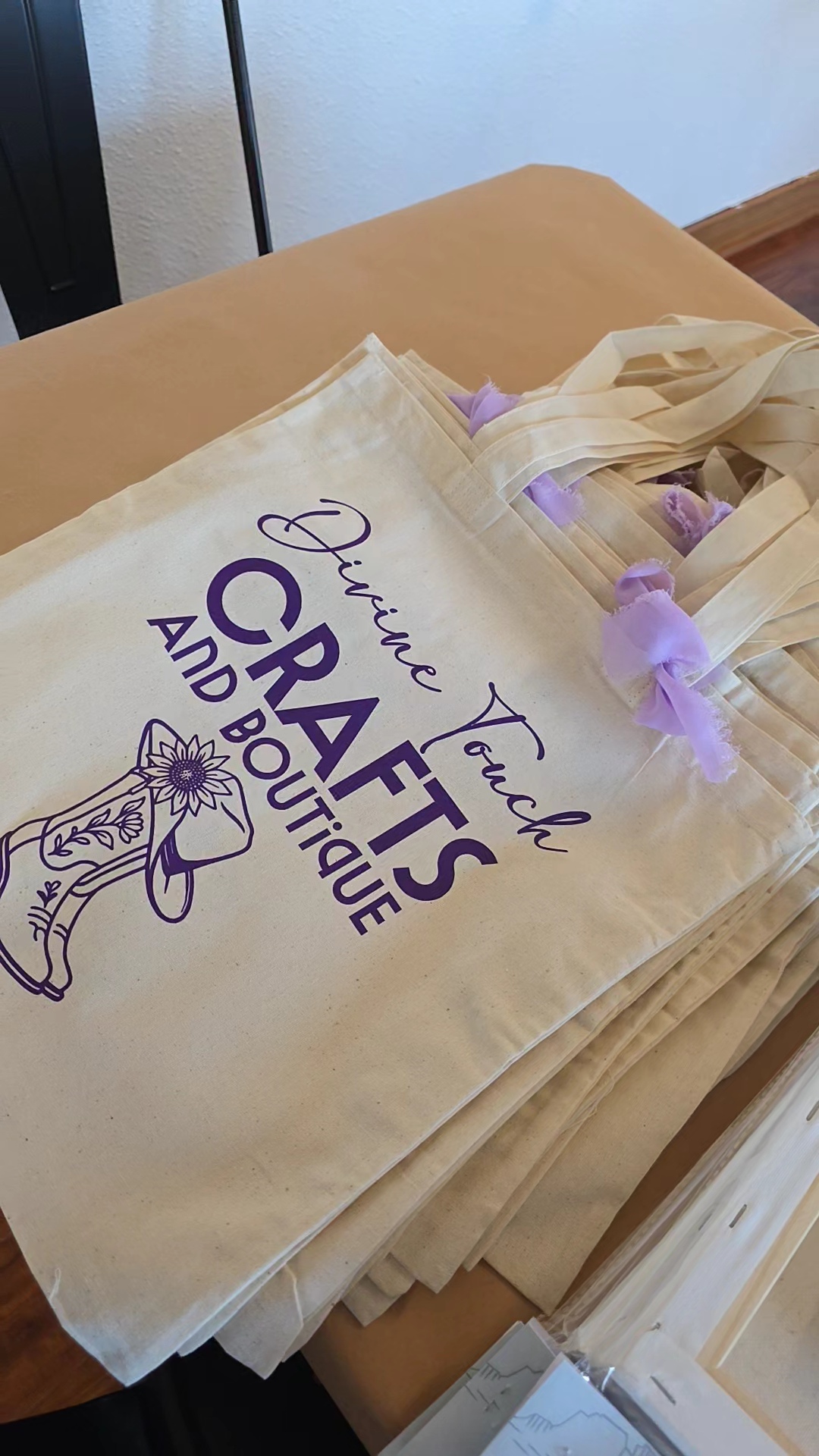 Cream-colored tote bag with purple text and a unicorn illustration, placed on a beige surface.