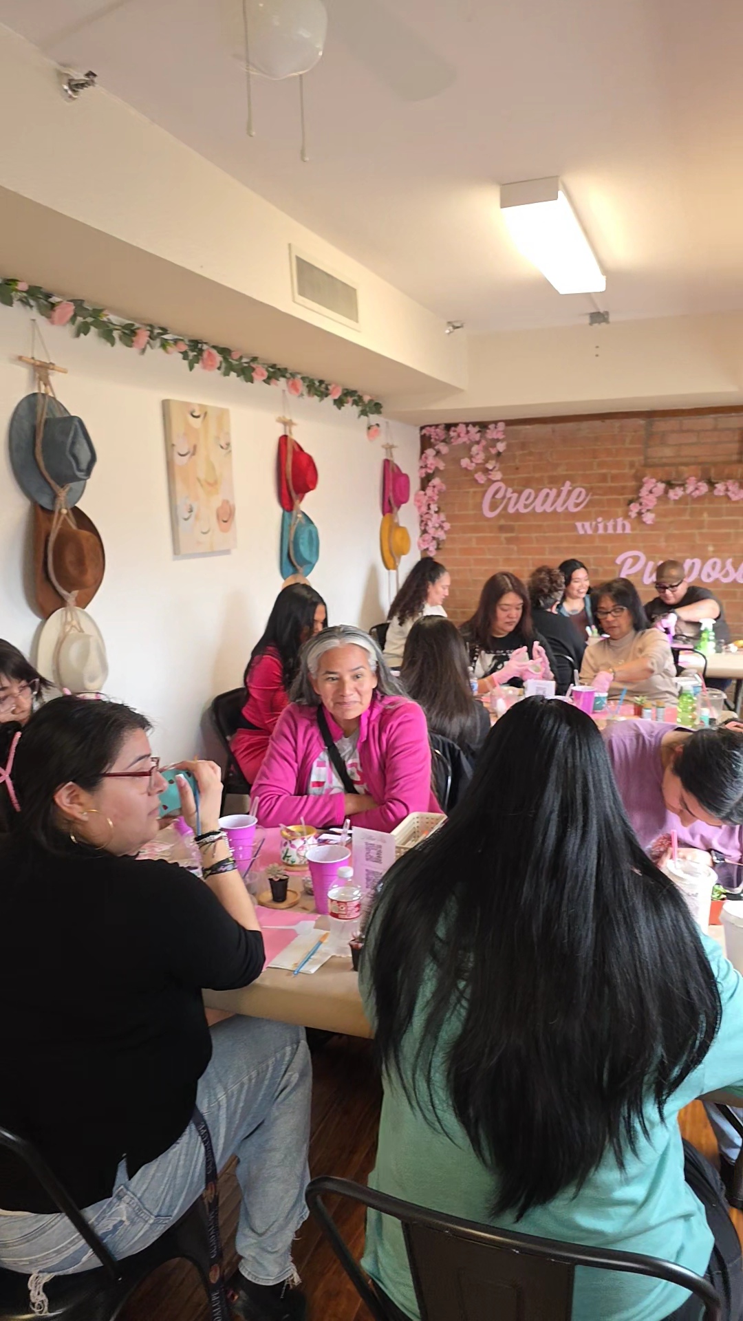 Group of women sitting at a table during a craft or social event in a decorated room.