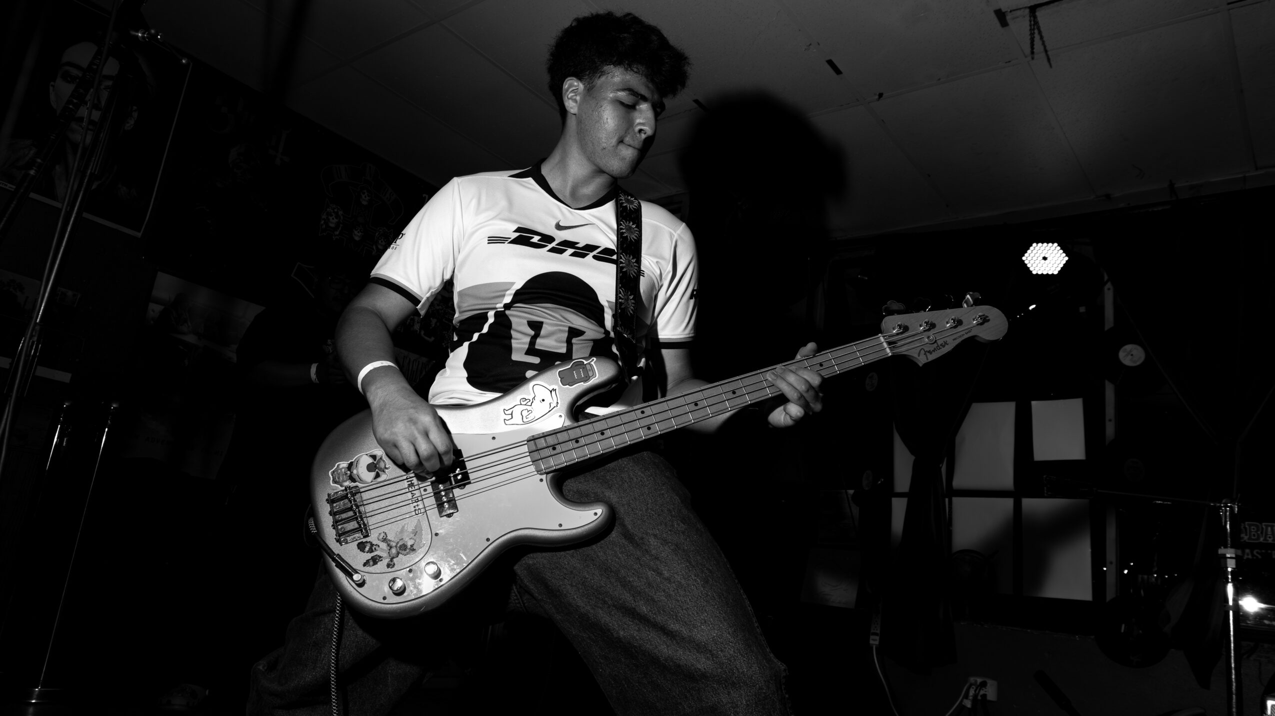 Young person playing bass guitar on stage in a dark room.
