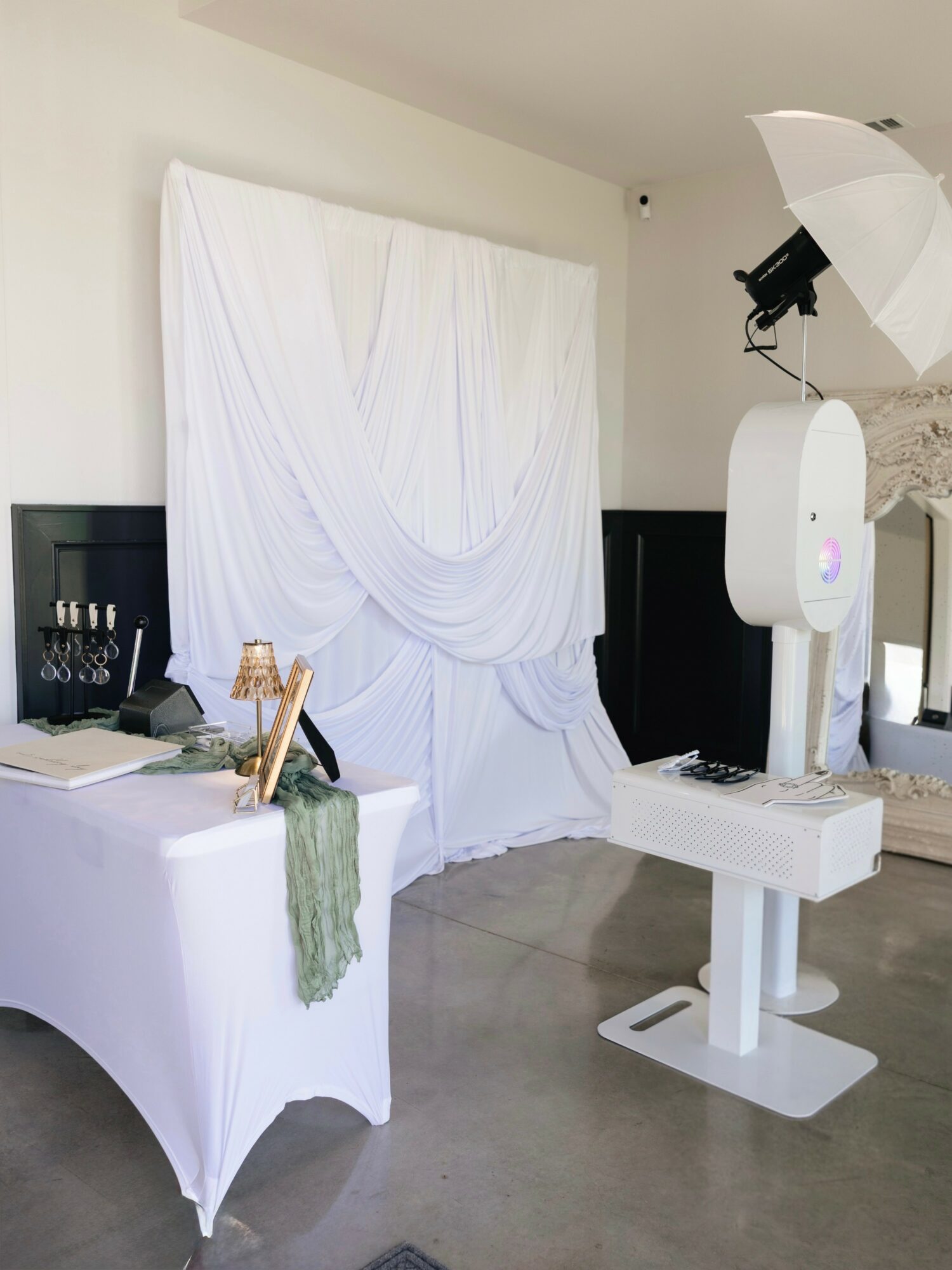White draped backdrop with black and white furniture and photography equipment in a room.