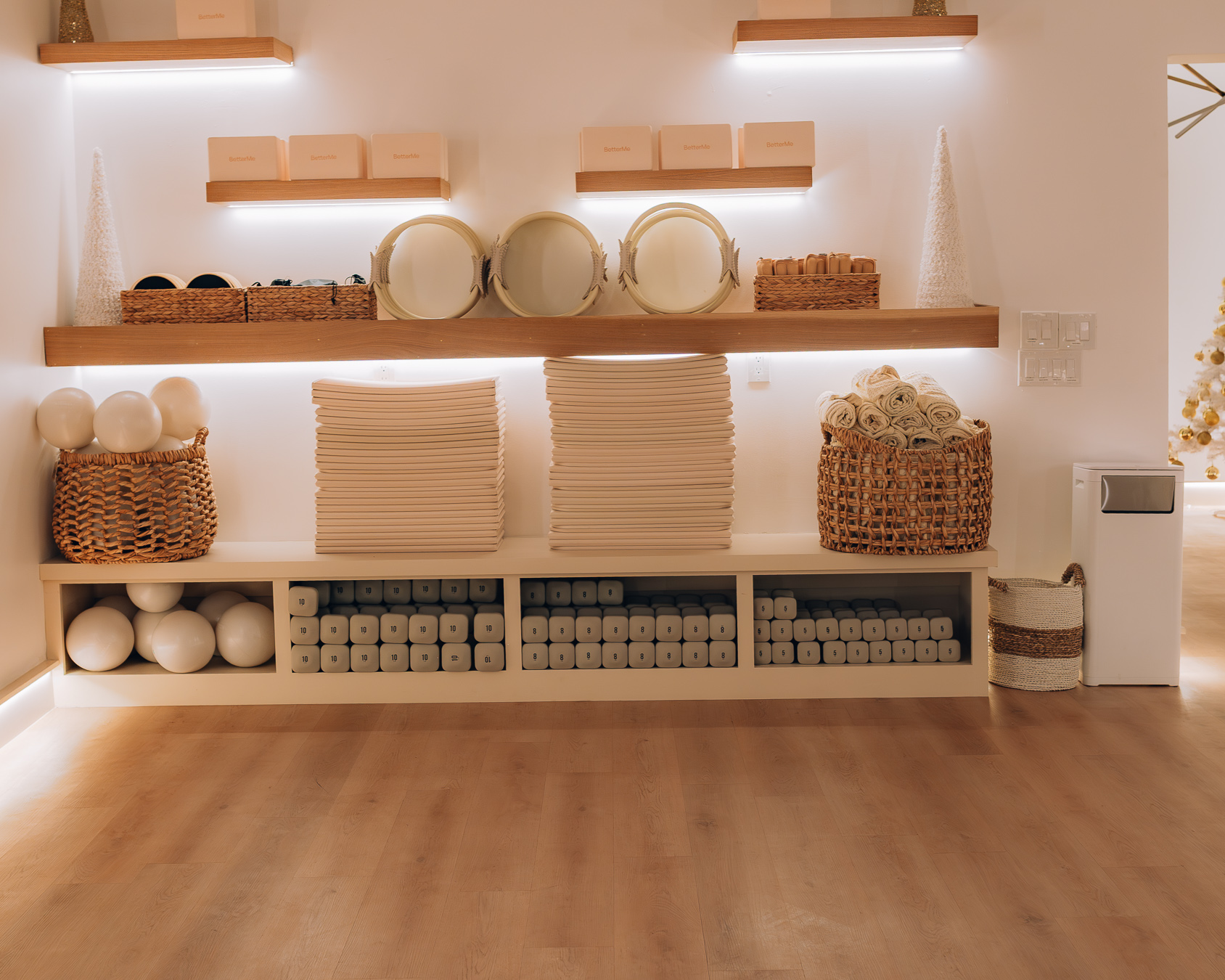 Shelves with plates, boxes, baskets, and stacks of paper or napkins, against a white wall with warm lighting.