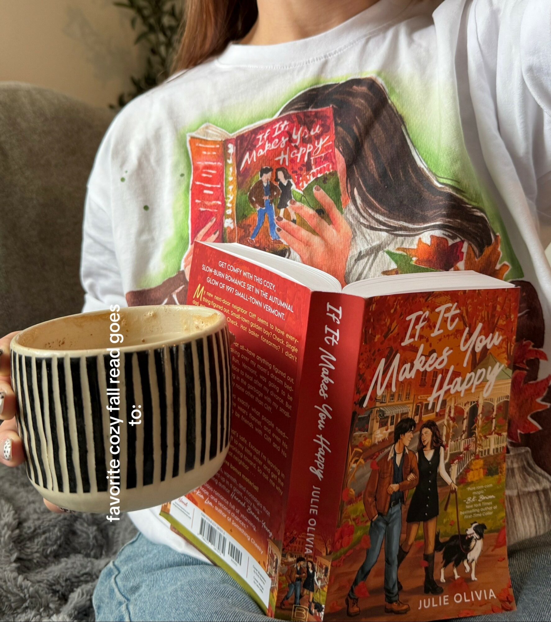Person holding a book with a red cover, a mug with black and white stripes, and a gray blanket.