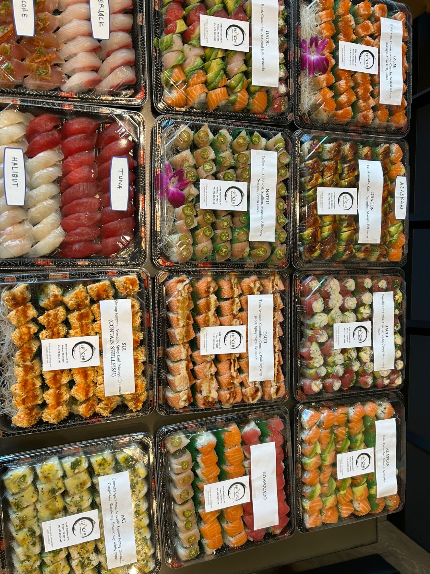 Assorted sushi rolls in plastic containers stacked on a shelf.