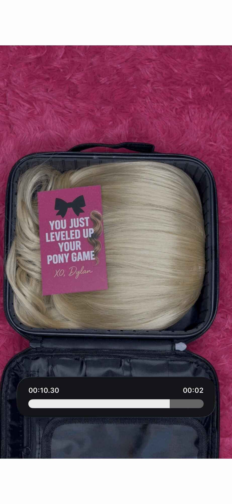 Open black case with blonde wig inside, pink sticker on wig says 'You just leveled up your pony game'.