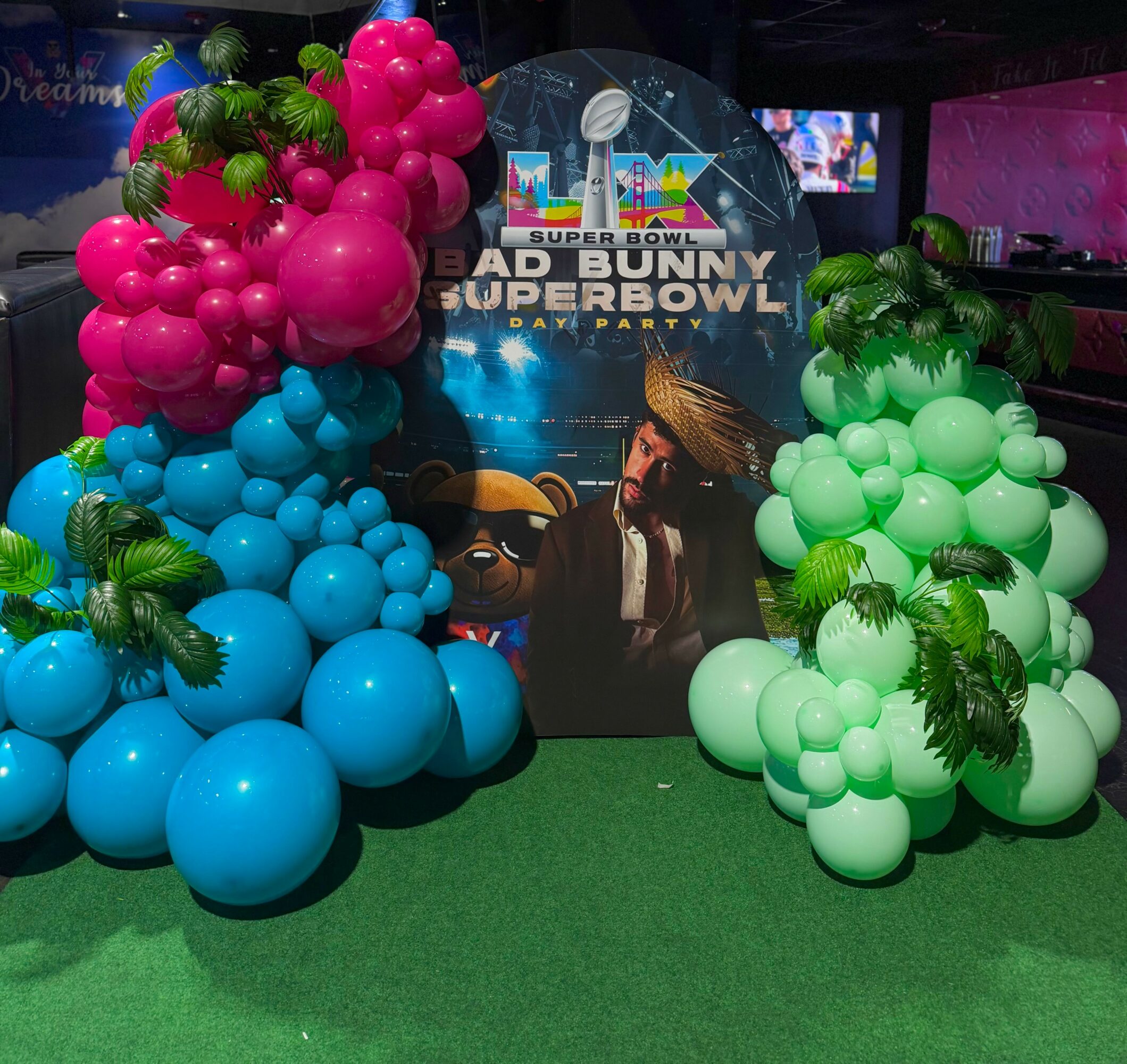 Decorative display with pink, blue, and green balloons, and a backdrop featuring characters from the Super Bowl event.