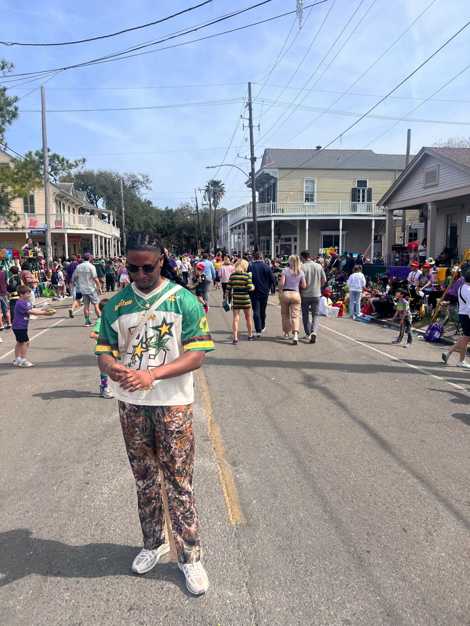 Person standing in the middle of a busy street during a festival or event, with crowds and buildings around.