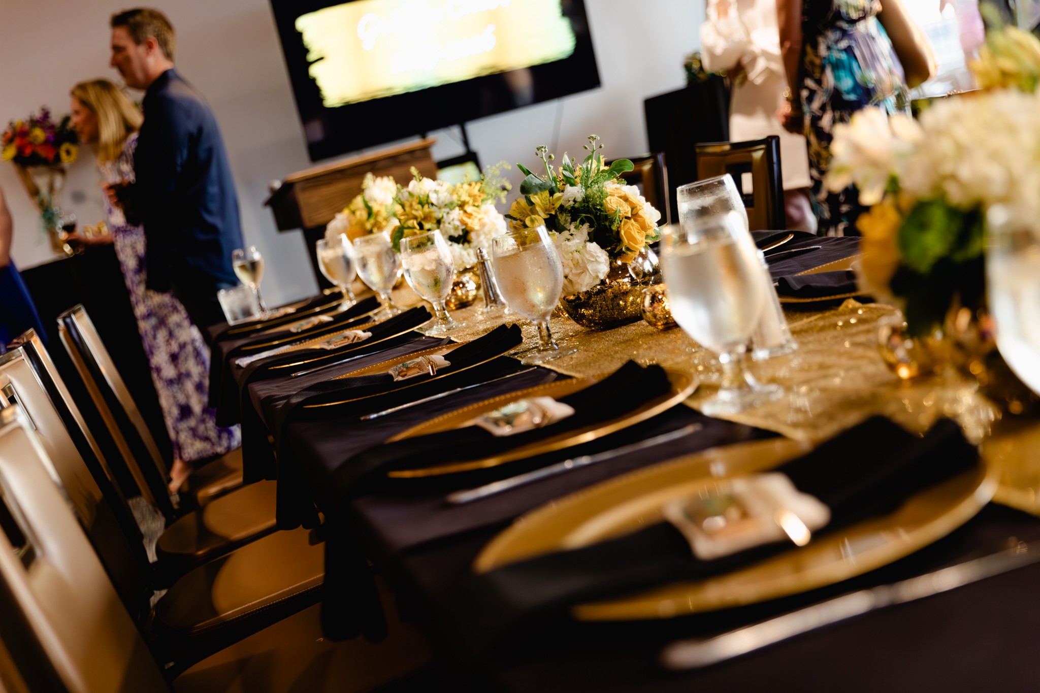 Table set with flowers, water pitchers, and place settings in a decorated room.