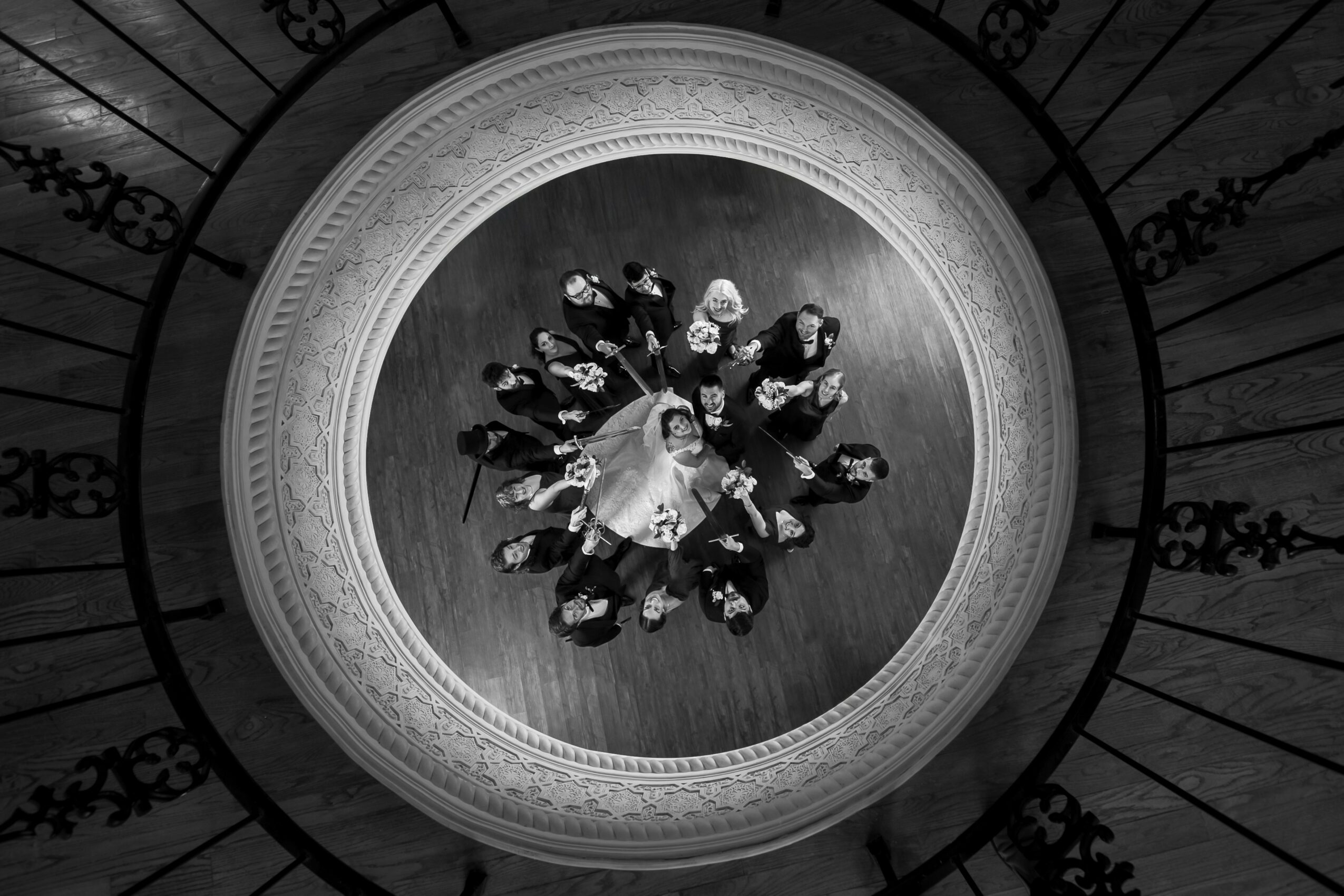 Top-down view of a group of people standing in a circle on a wooden floor, viewed through a circular opening.