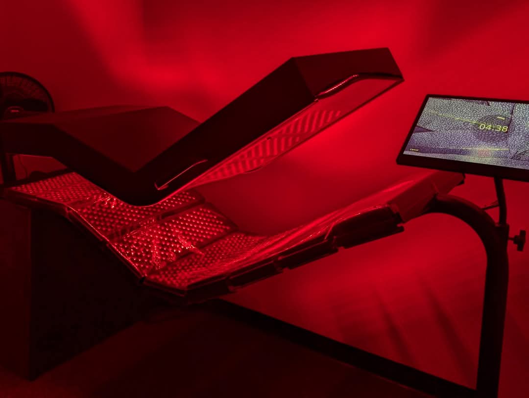 Medical or laboratory equipment with red lighting, a monitor, and a flat surface, in a dark room.