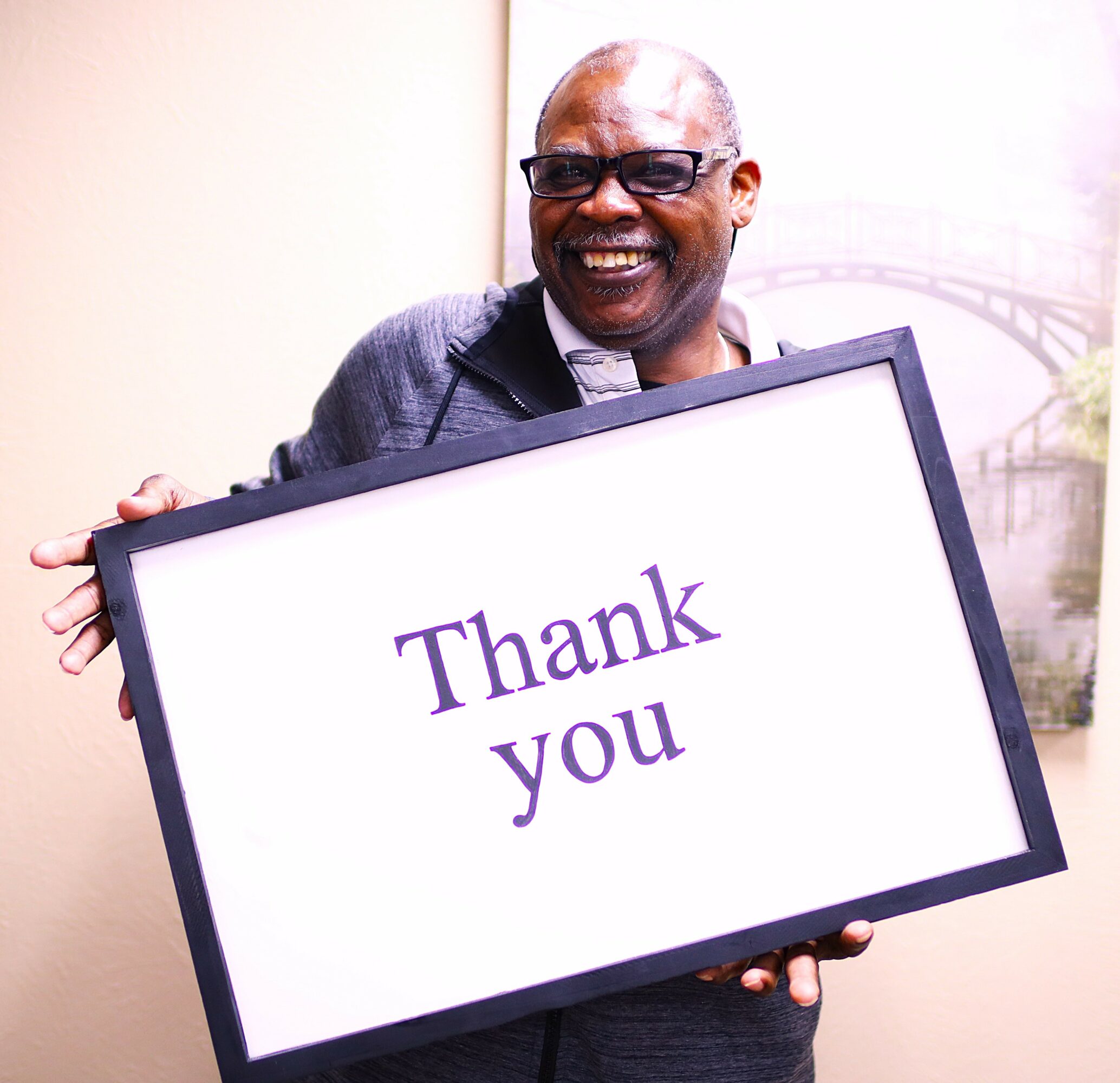 Smiling man holding a sign that says 'Thank you'.