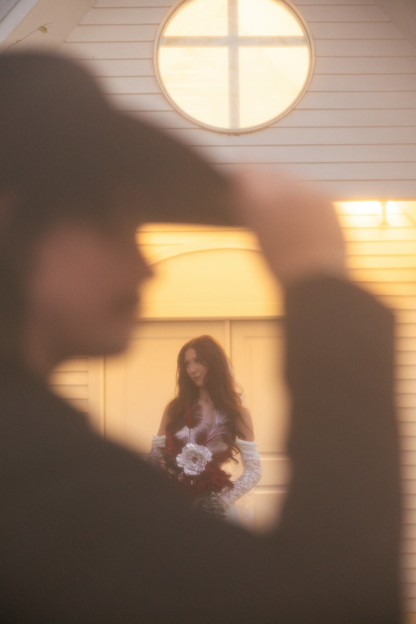 Blurred foreground with a woman holding flowers in the background, inside a building with a circular window.