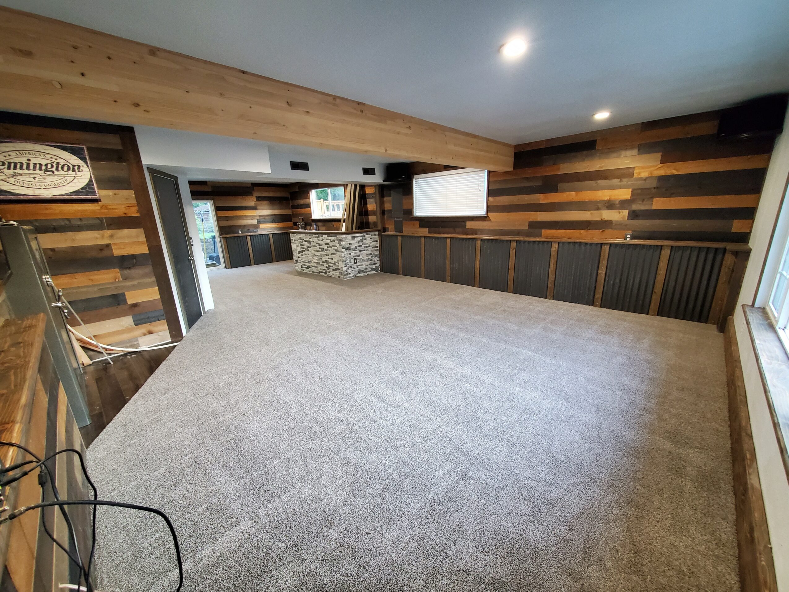 Empty room with carpeted floor, wooden wall paneling, and a window on the right side.