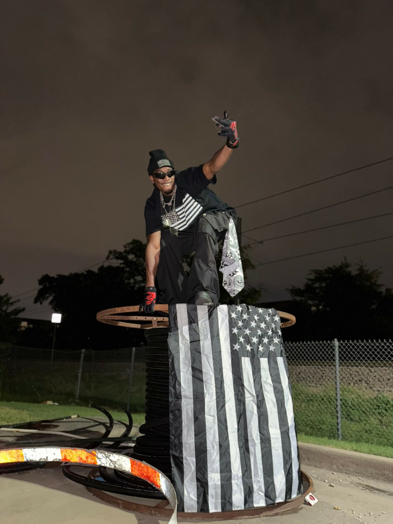 Person standing on a platform holding a flag with a black and white striped design, dark sky background.