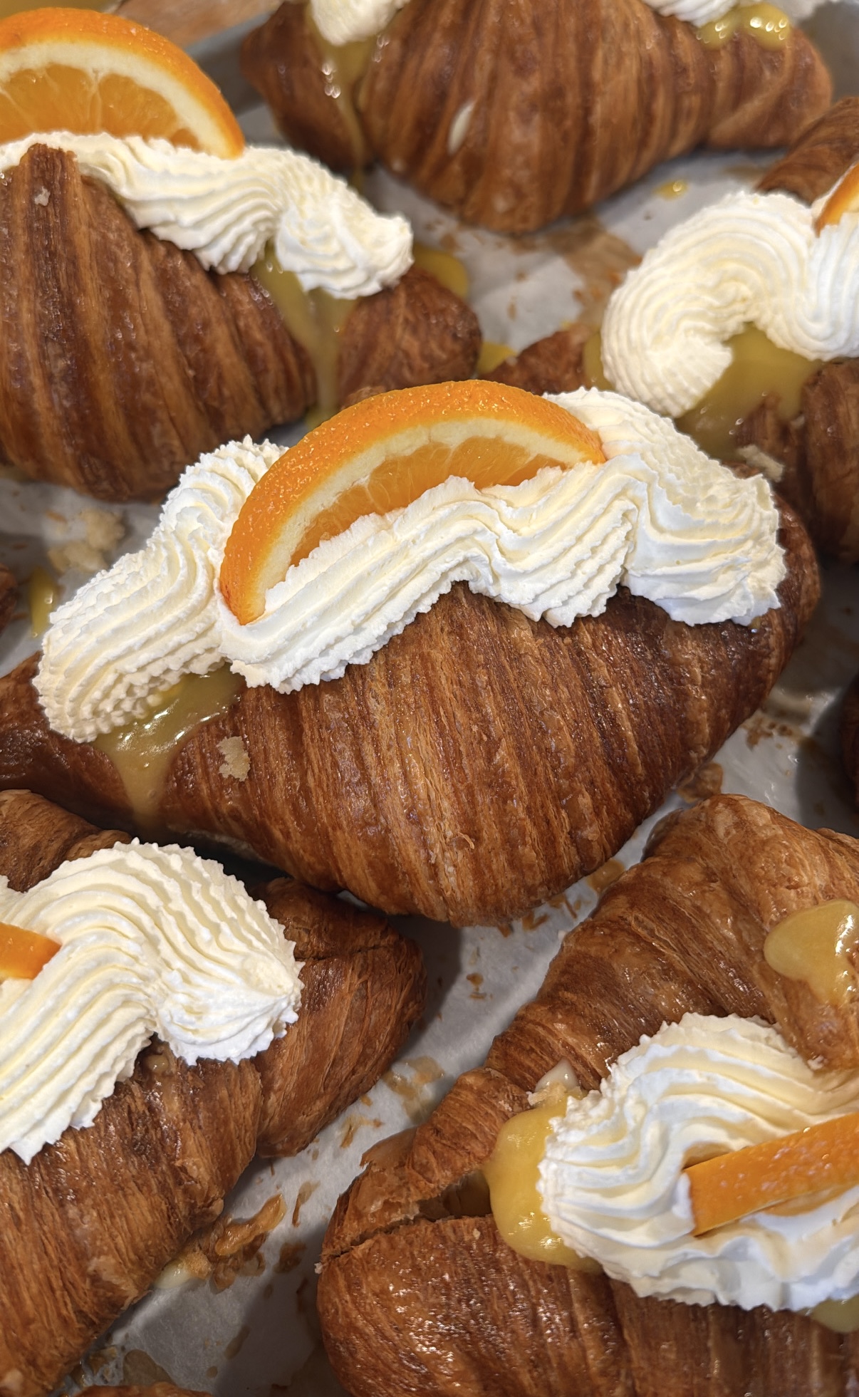 Cakes topped with whipped cream and orange slices, arranged on a tray.