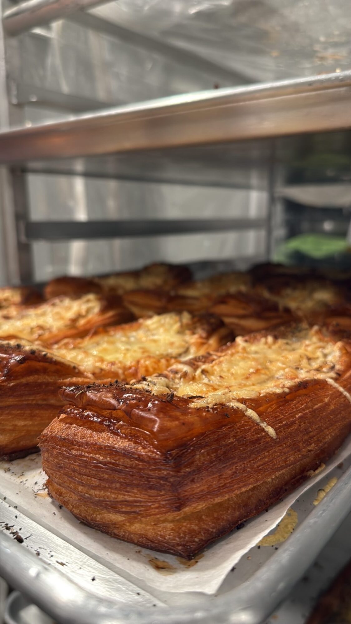 Baked layered pastry with a golden-brown crust on a tray, viewed from the side.